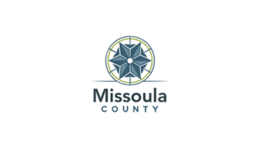 “Missoula COUNTY” below a blue and teal six-sided star surrounded by a blue circle highlighted in lime green