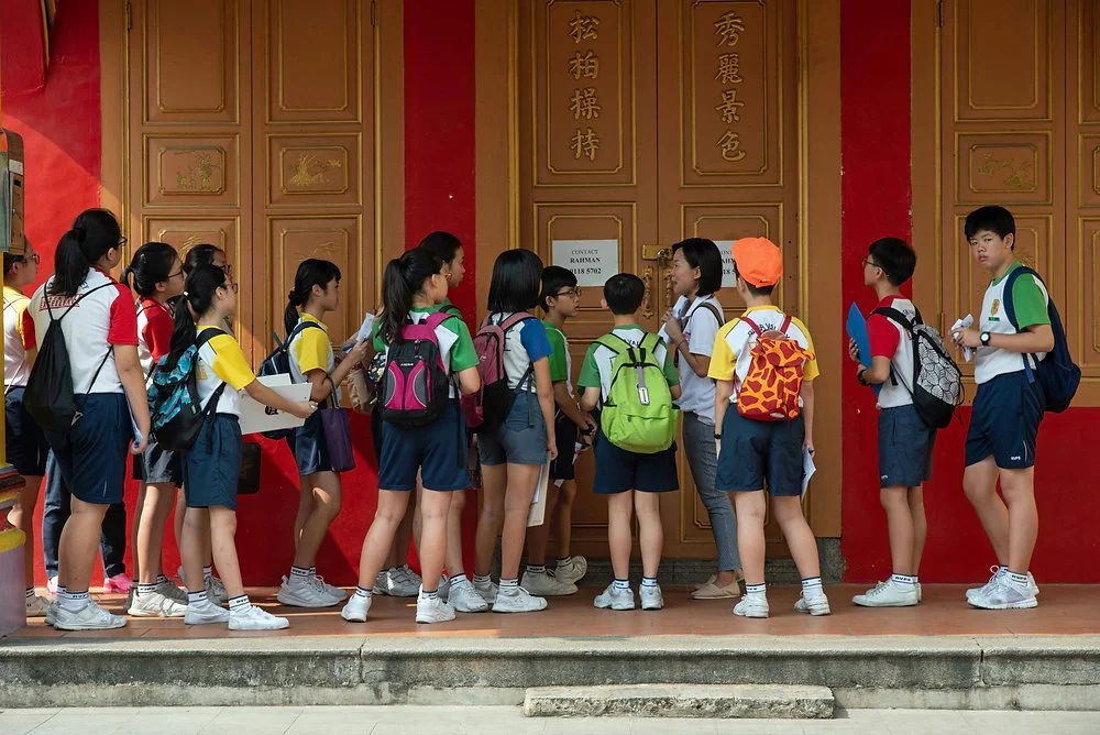 Primary school students in uniform gathered at a school doorway