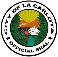 Official seal of the City of La Carlota, featuring a mountain, sun, tree, river, and a person with open arms