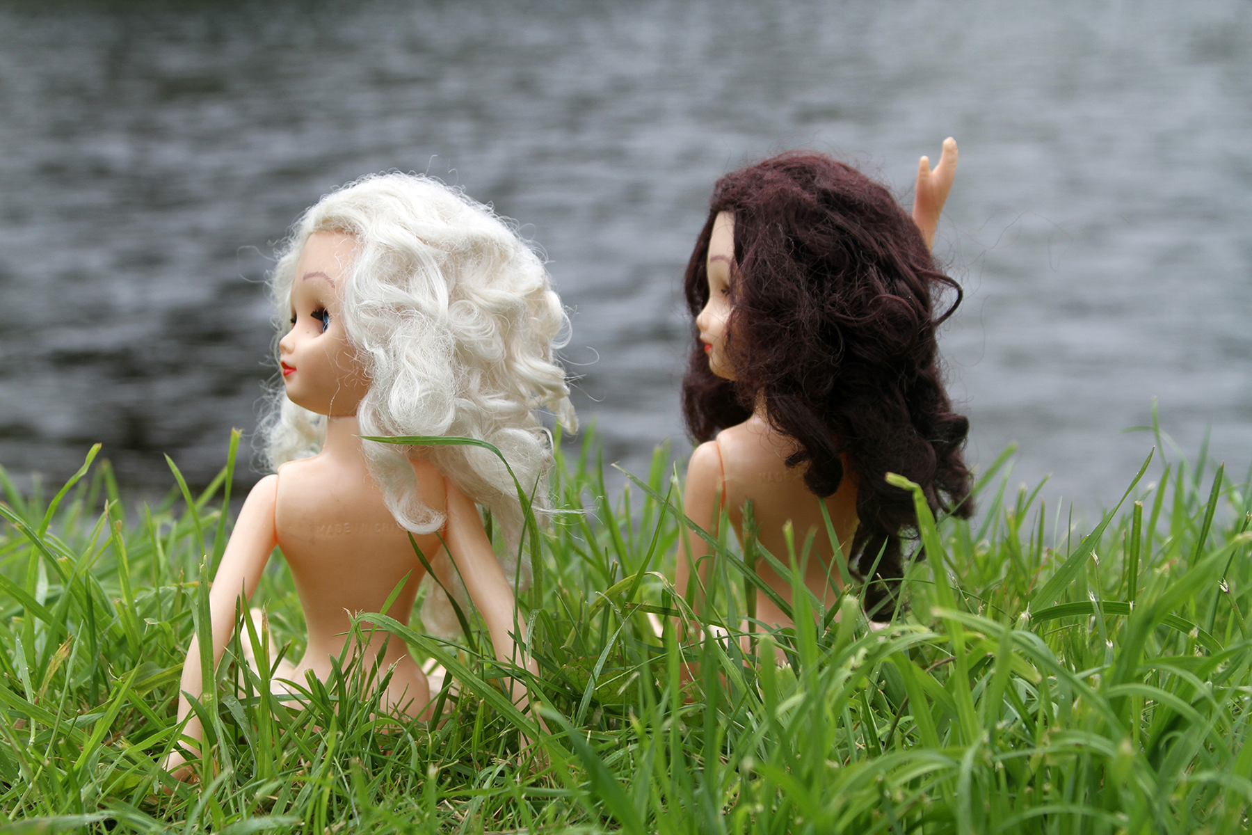 Paige and Ginger from behind and seeing their faces from the side, sitting along the River Ness in Scotland and waving hello to passerby