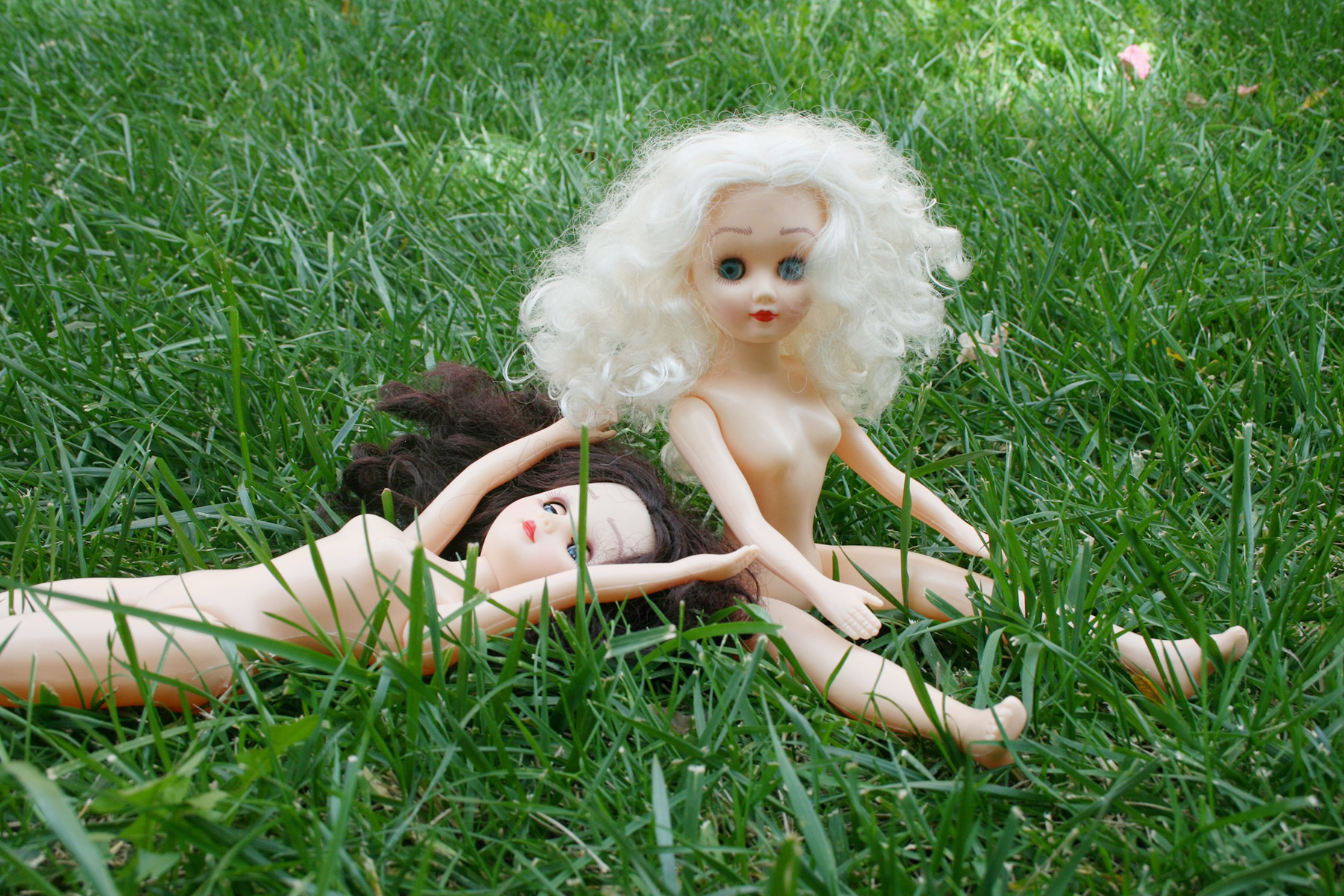Paige and Ginger on Grass, Ginger is seated and sitting upright while Paige is laying down with arms over head and eyes closed.