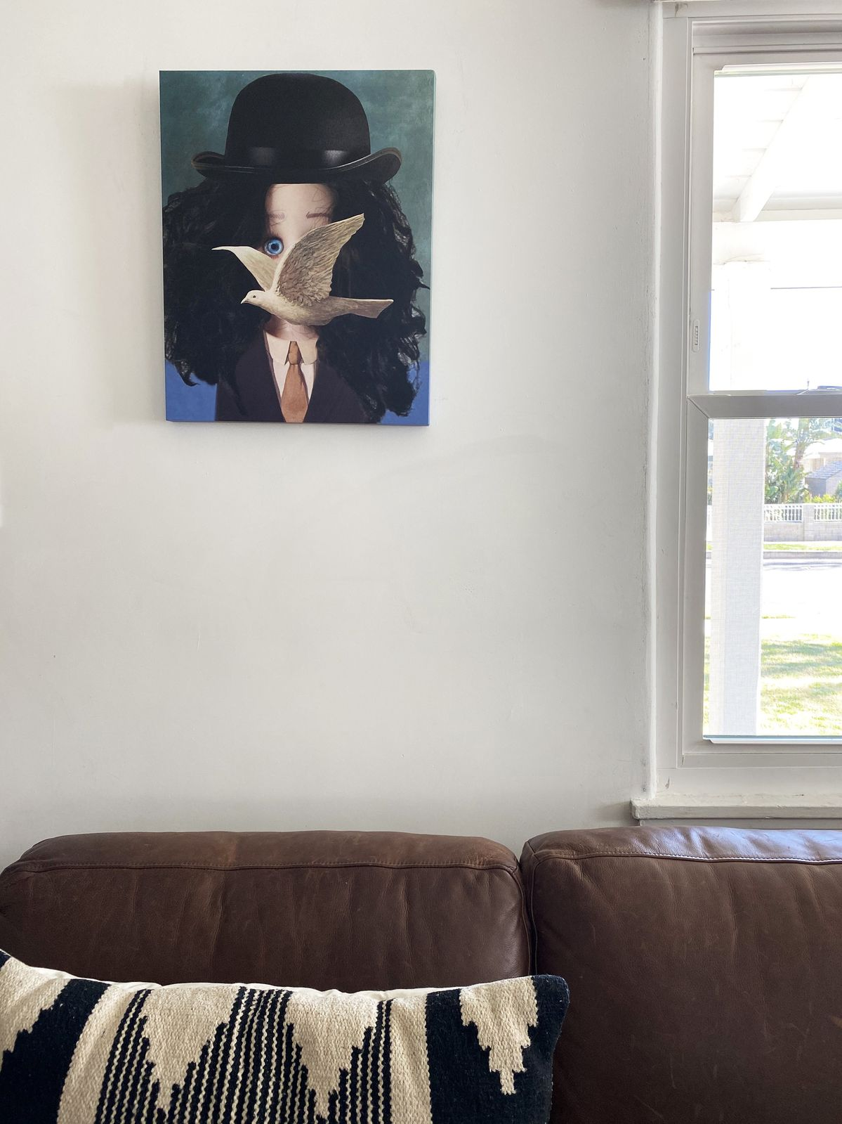 Magritte style Paige in Bowler hat with bird covering most of face, on cavas in living room