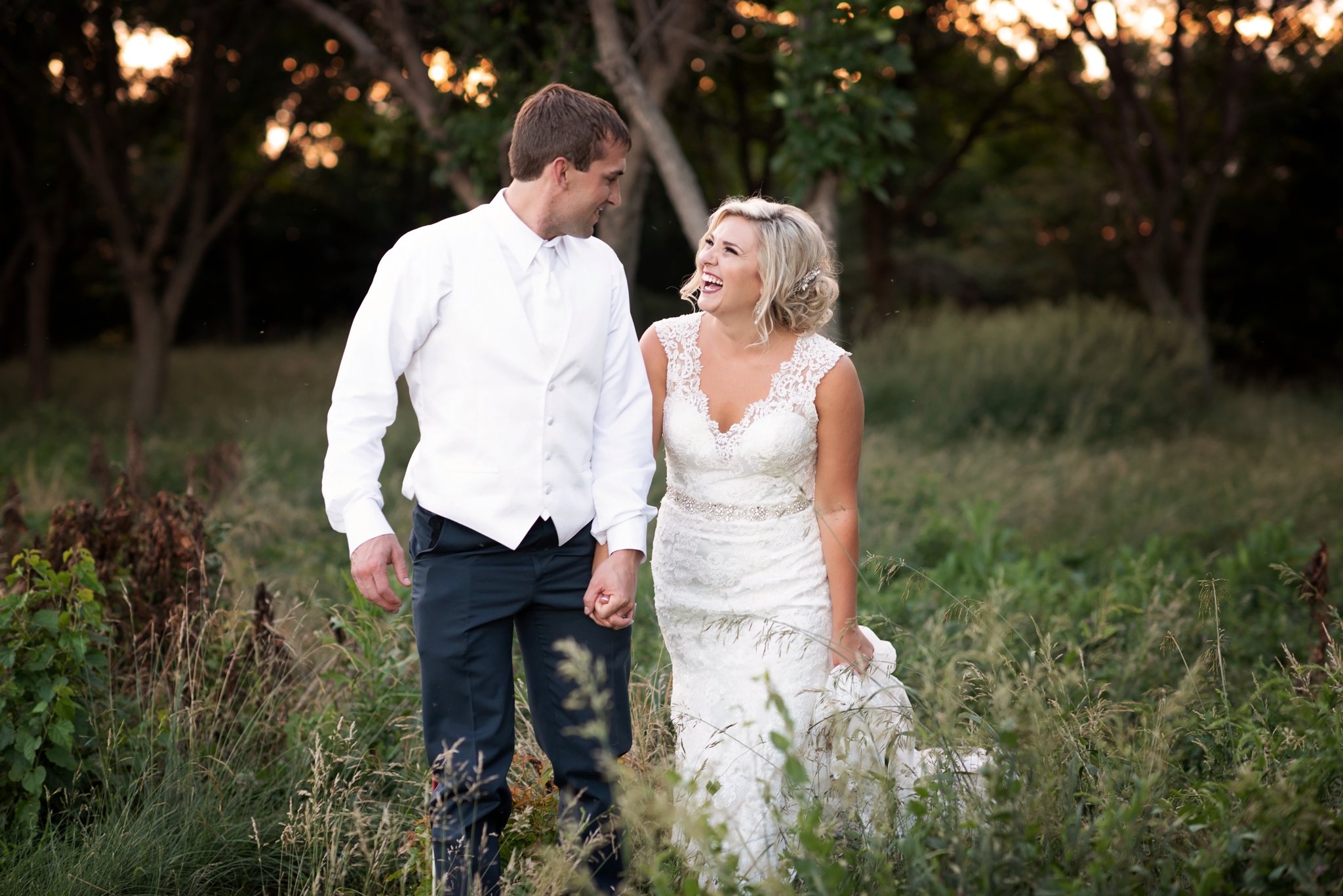 bride and groom walk through forest together