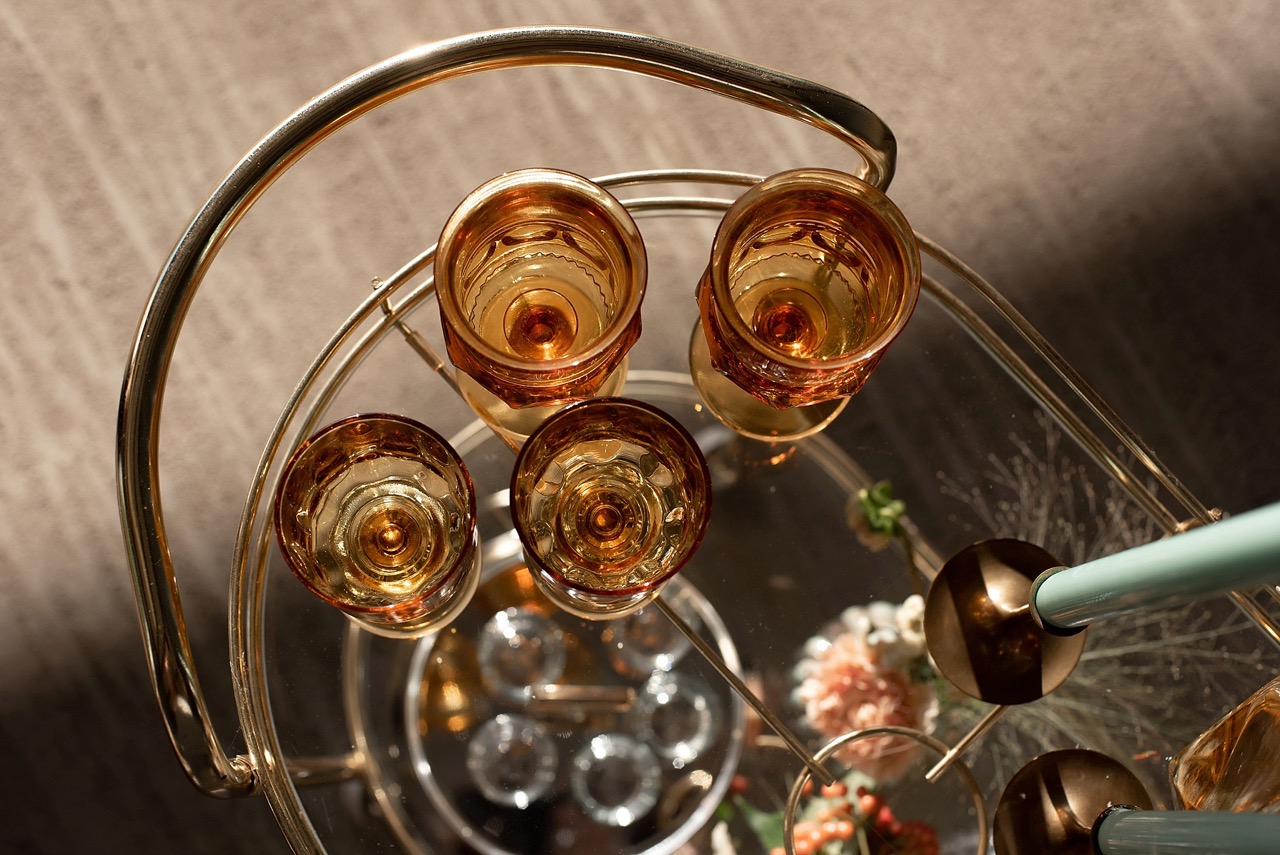 orange colored glass goblets on glass and gold bar cart