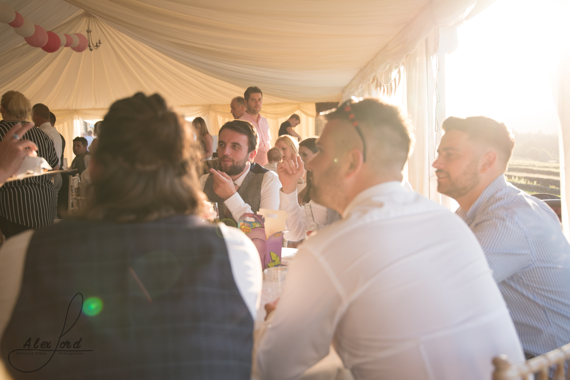 July sunlight floods the marque full of wedding guests