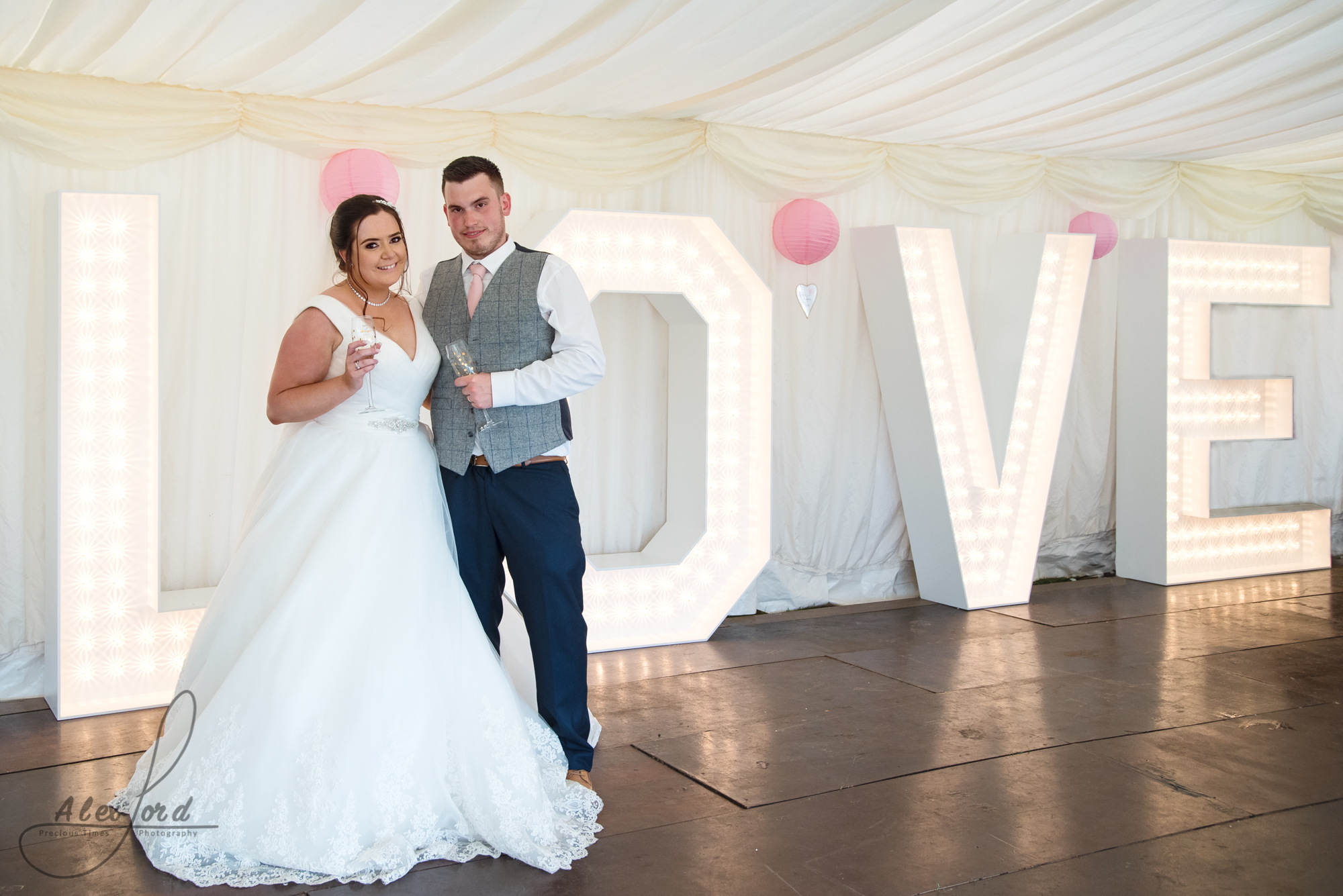 The bride and groom pose together in front of their giant love letters