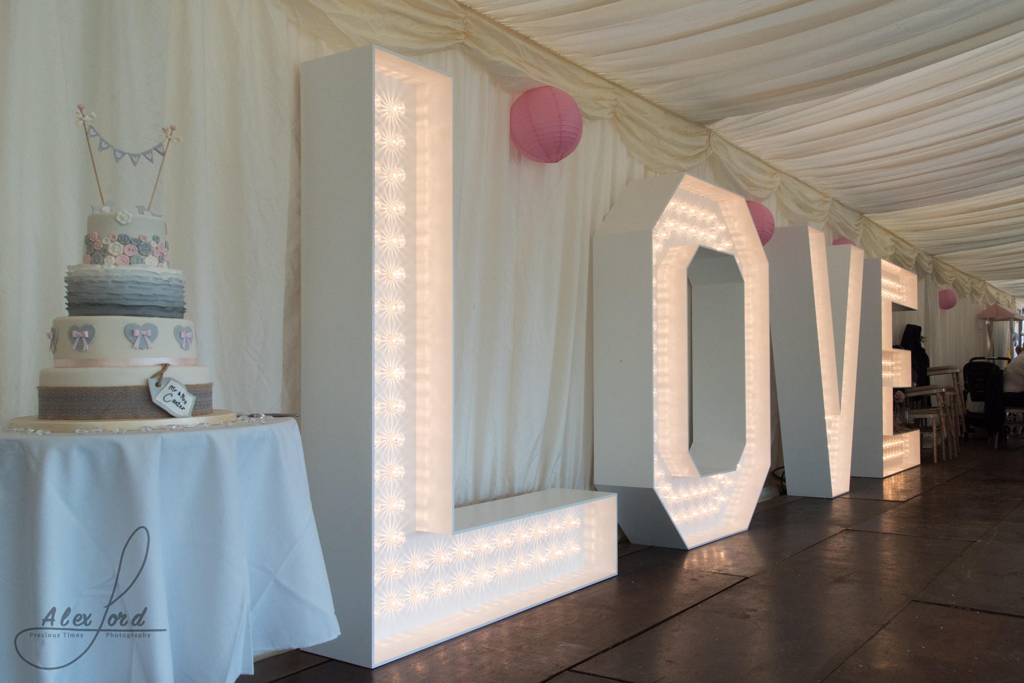 Giant love letters sit next to the wedding cake in the reception marquee