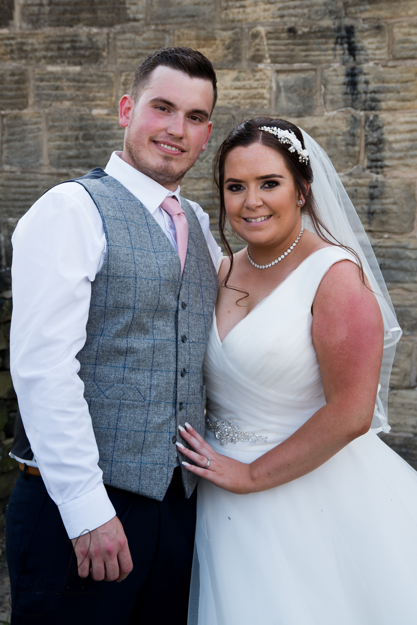 Bride and groom pose for a photo facing the camera with their heads leaning in towards each other