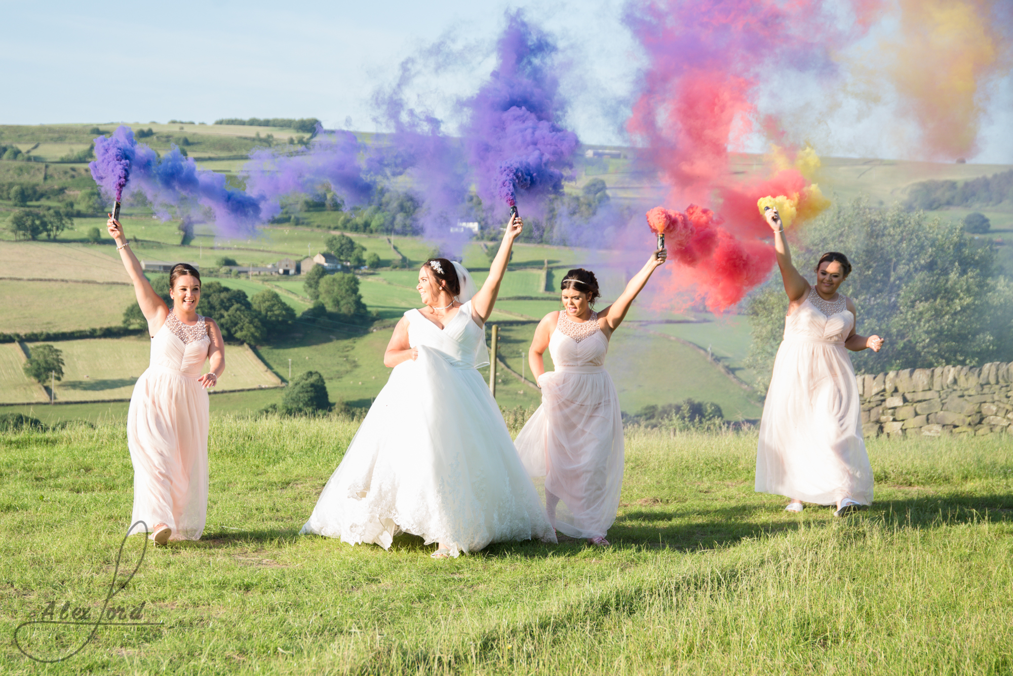 Purple and red smoke bombs light the sky as the bride and bridesmaids run towards the camerq