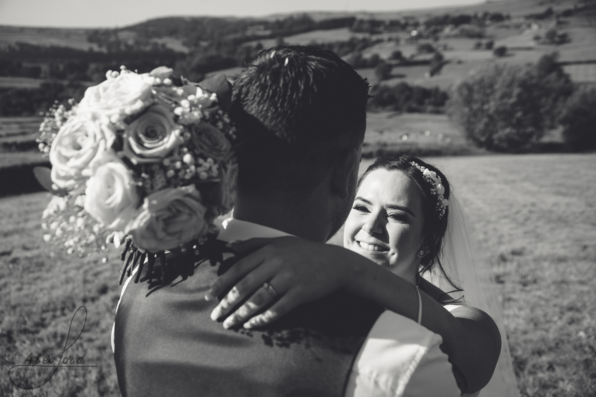 The bride embraces the groom with her bouquet of flowers round the grooms neck 