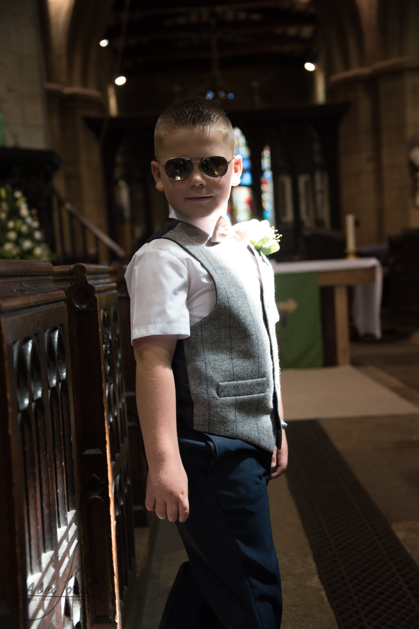 A young usher stands in church and poses for the camera, he’s wearing cool sunglasses