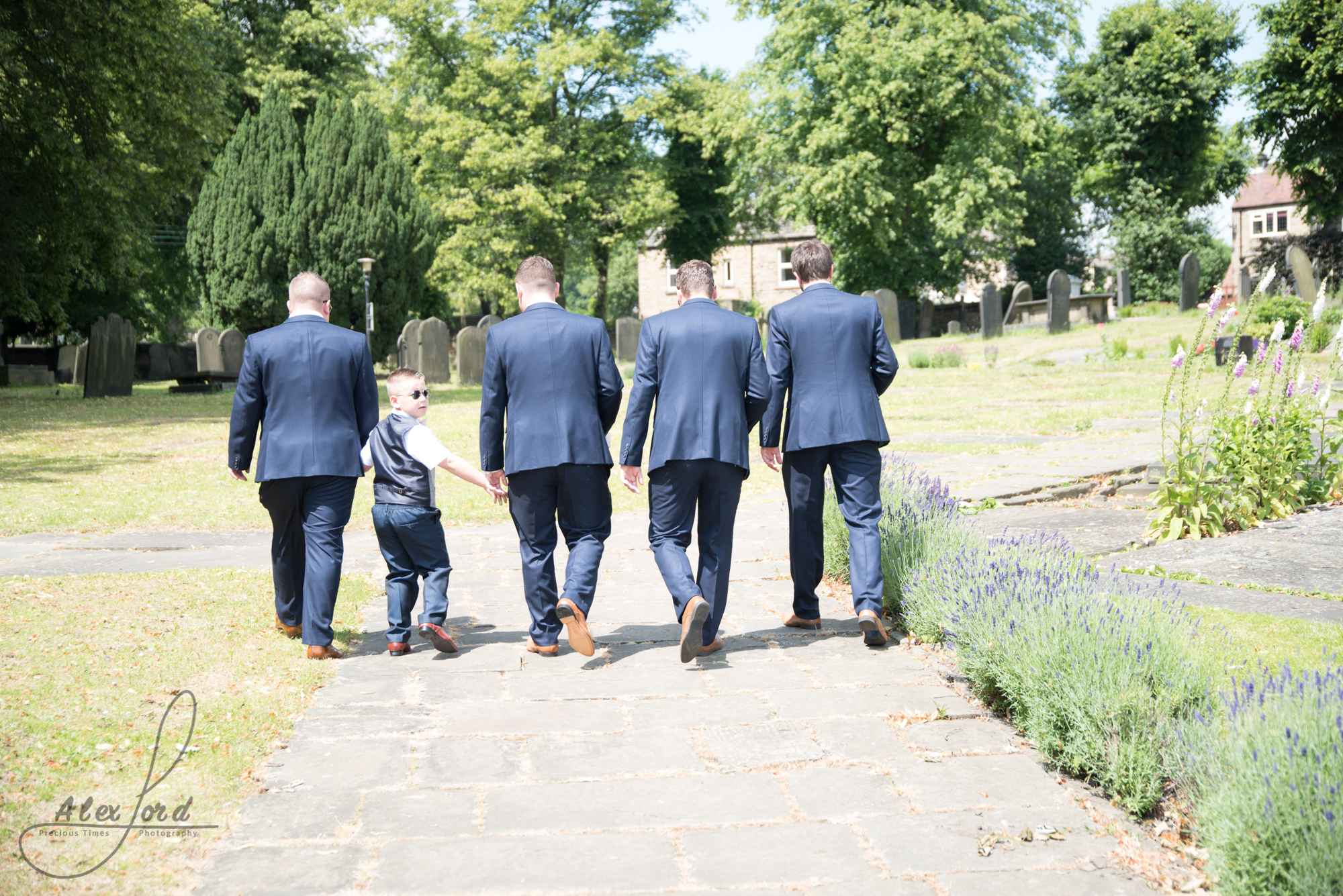  Groom, three ushers and the page boy walk towards the church on a hot sunny day