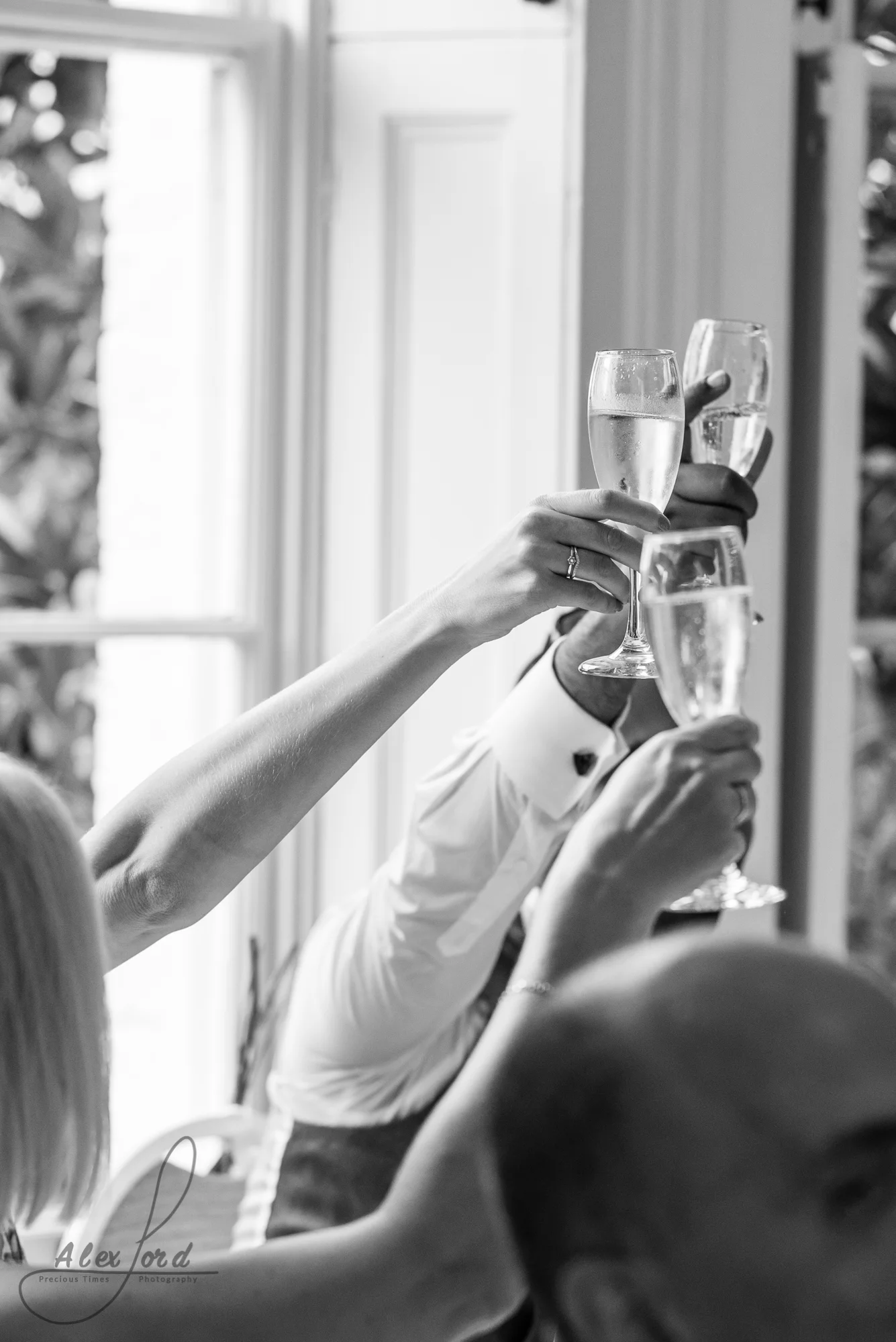 Three members of the wedding party holding up champagne glasses for a toast during the wedding breakfast speeches