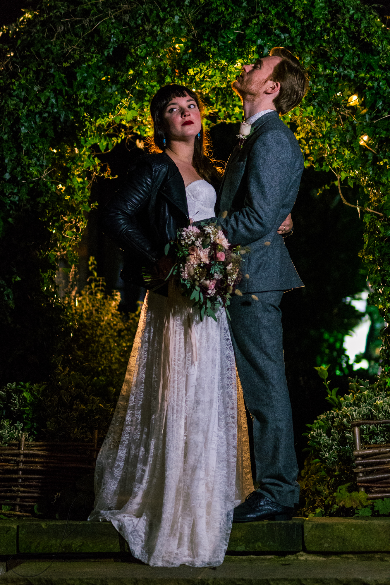 the bride and groom all lit up outside their wedding venue at night