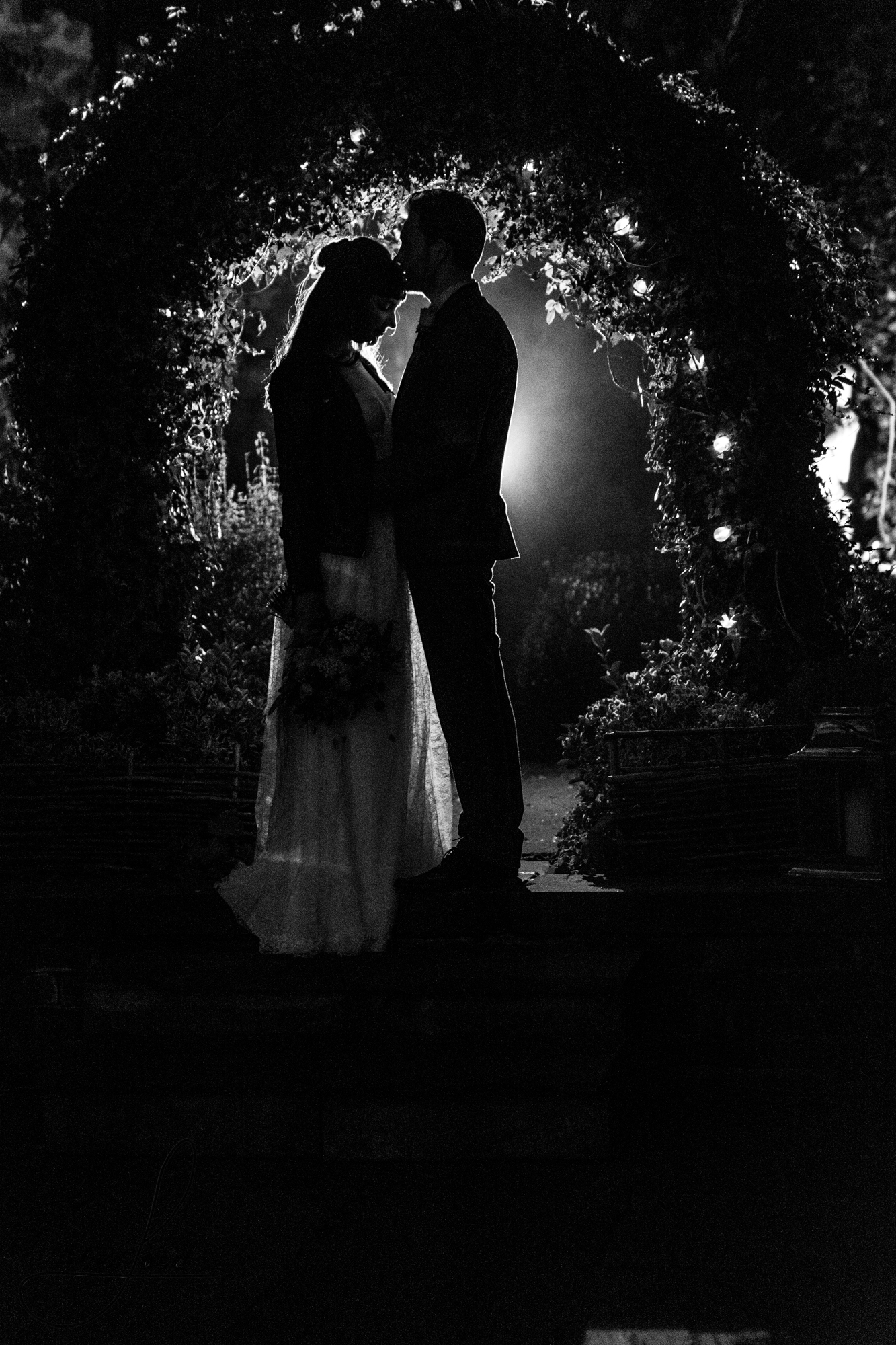 a black and white photo of the bride and groom outside their wedding venue at night