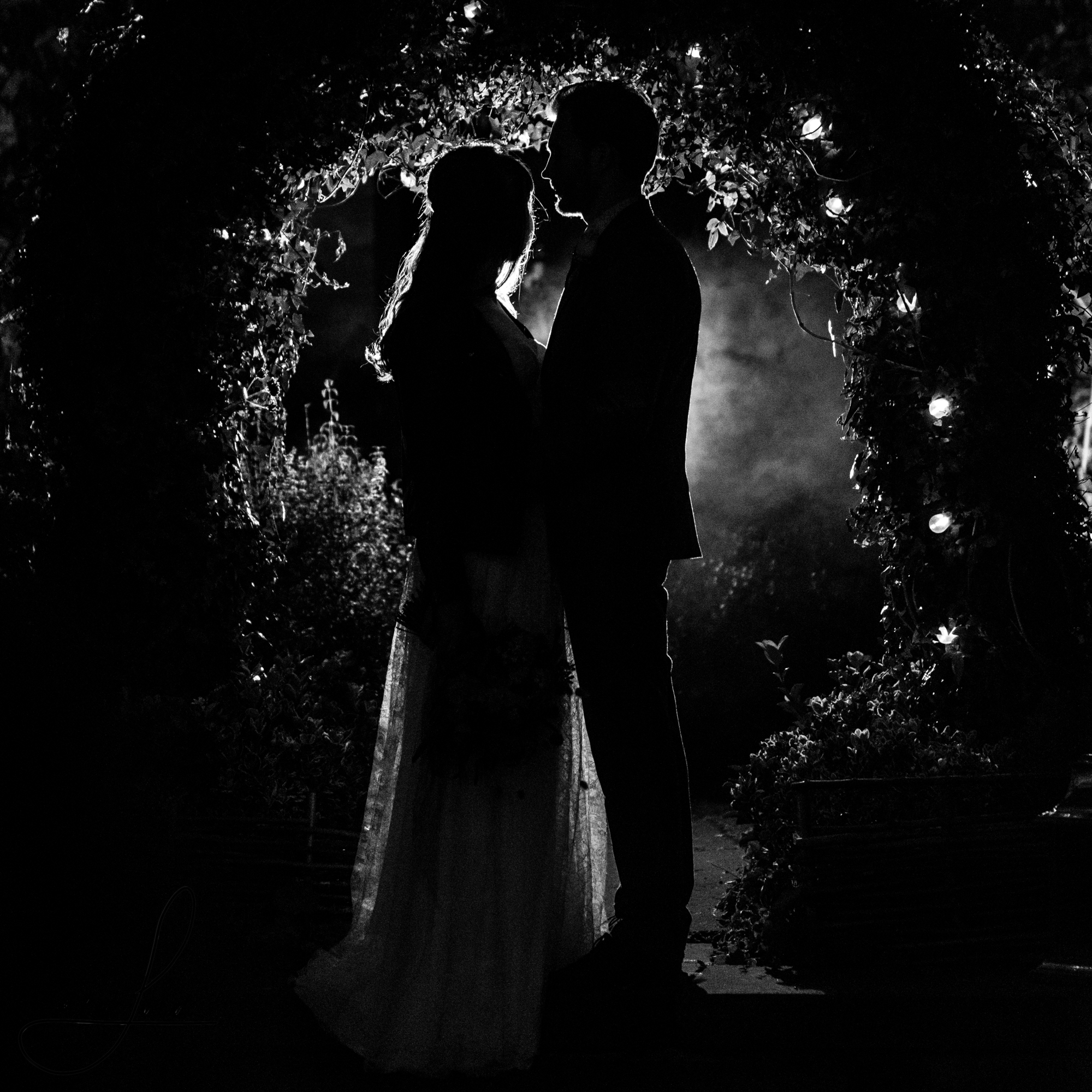 a single flash backlights the bride and groom for a photography shoot outside their wedding venue