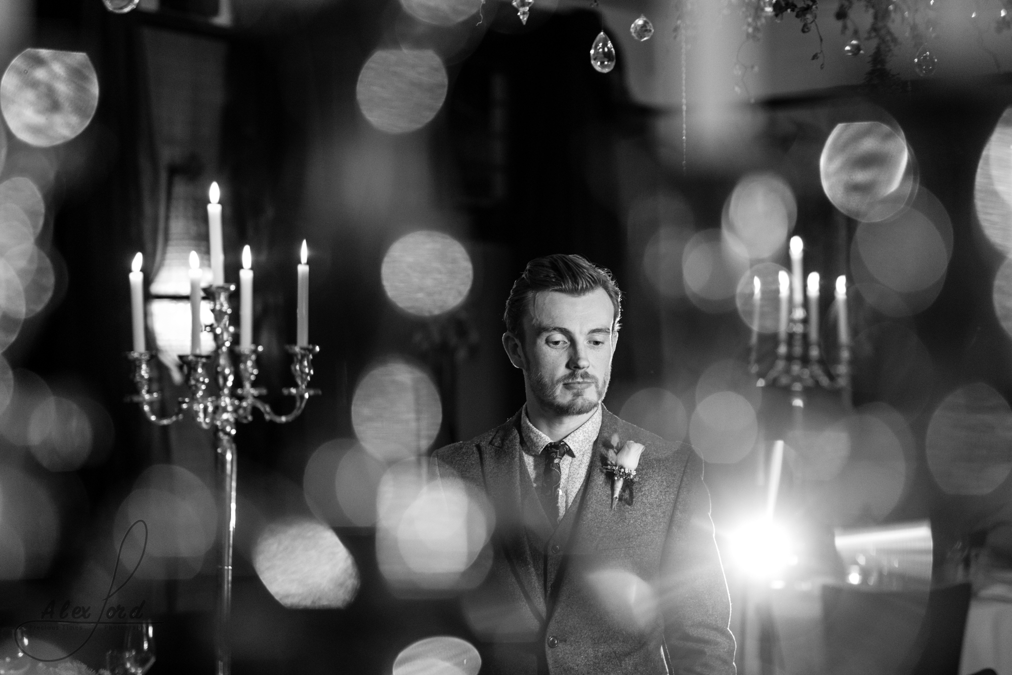 a black and white image of the groom inside the wedding venue lit up with candles