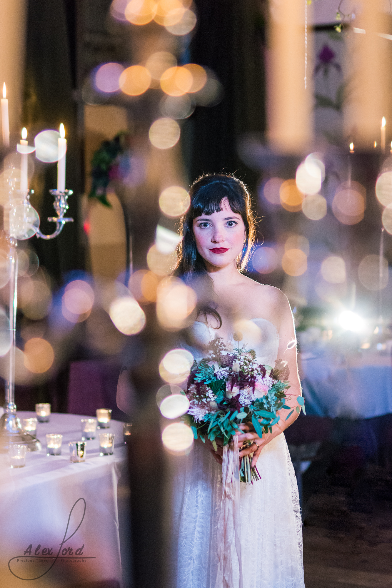 the bride stands on her own surrounded by candles in her wedding venue in cheshire