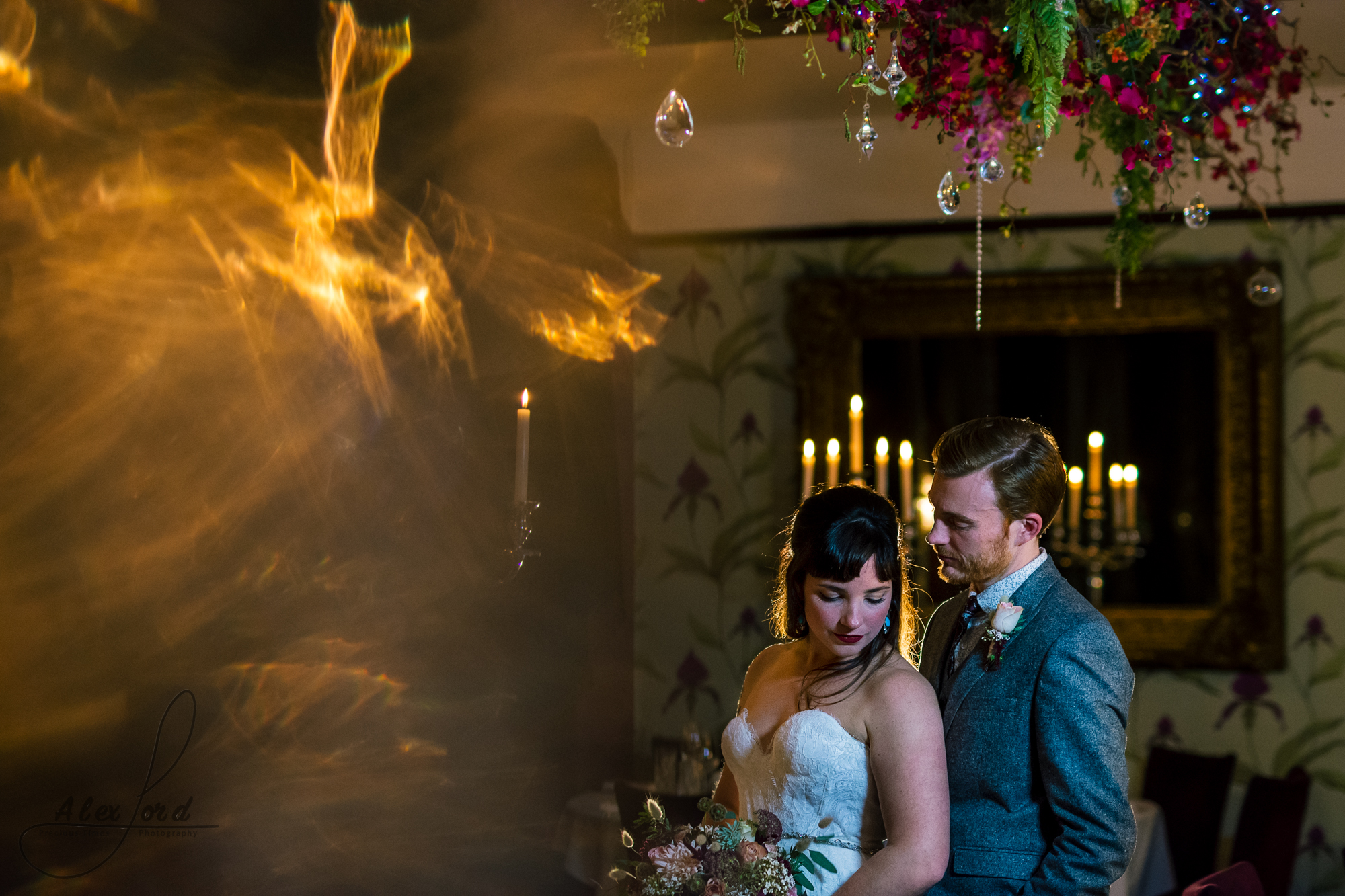 photo of the bride and groom together standing looking towards the ground surrounded by candles