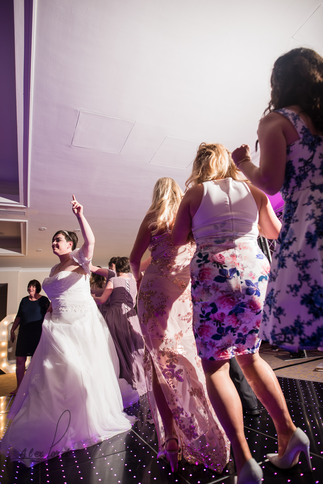 the bride leads other wedding guests as they dance around the dance floor