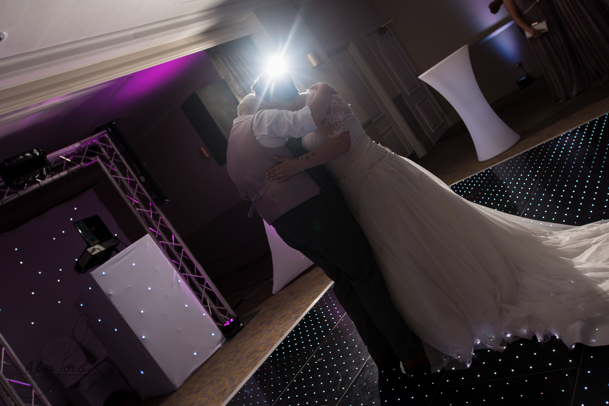 the bride and bride are lit with a single flash behind their heads as they share their first dance together as wife and wife