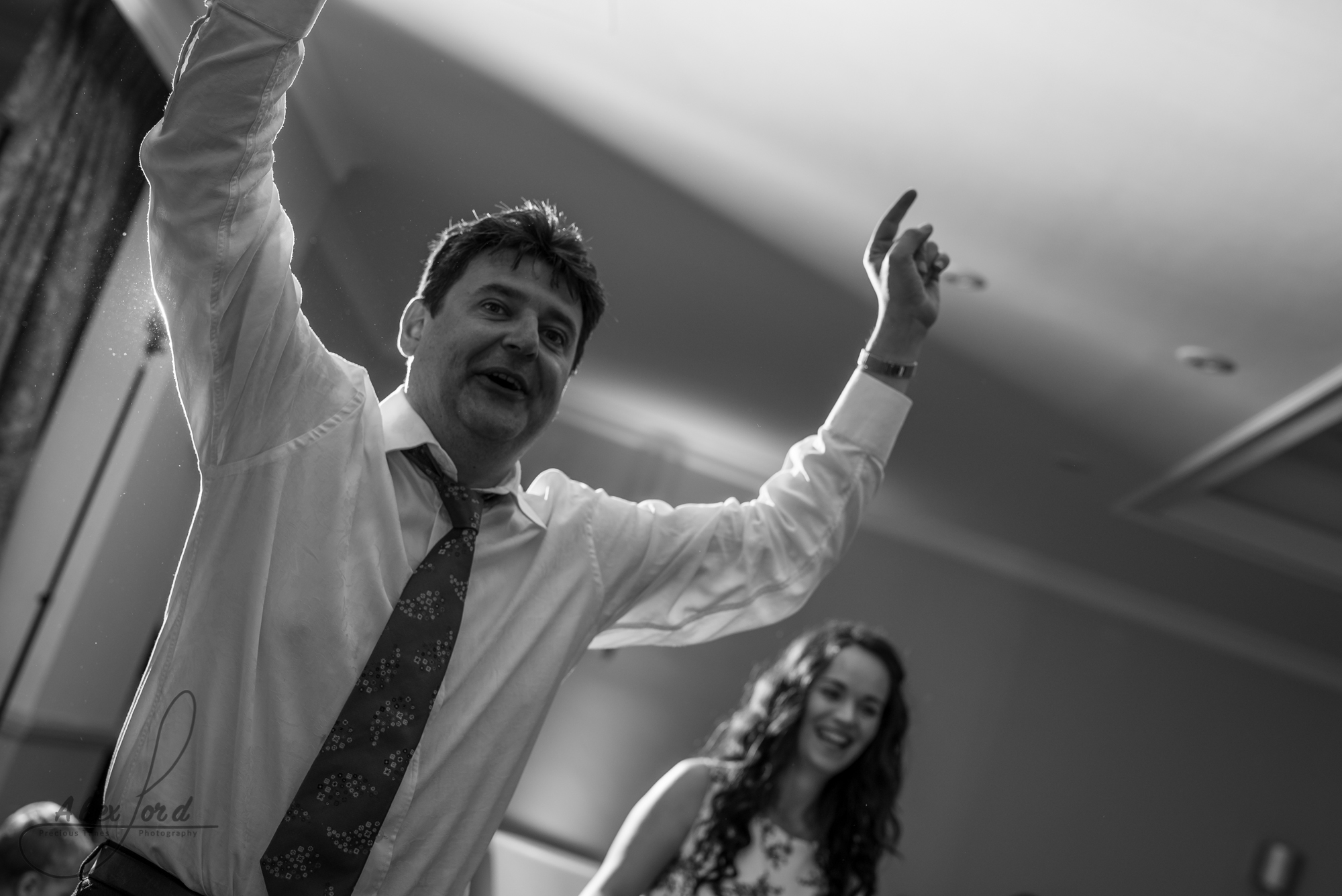 a male wedding guest puts his arms up in the air