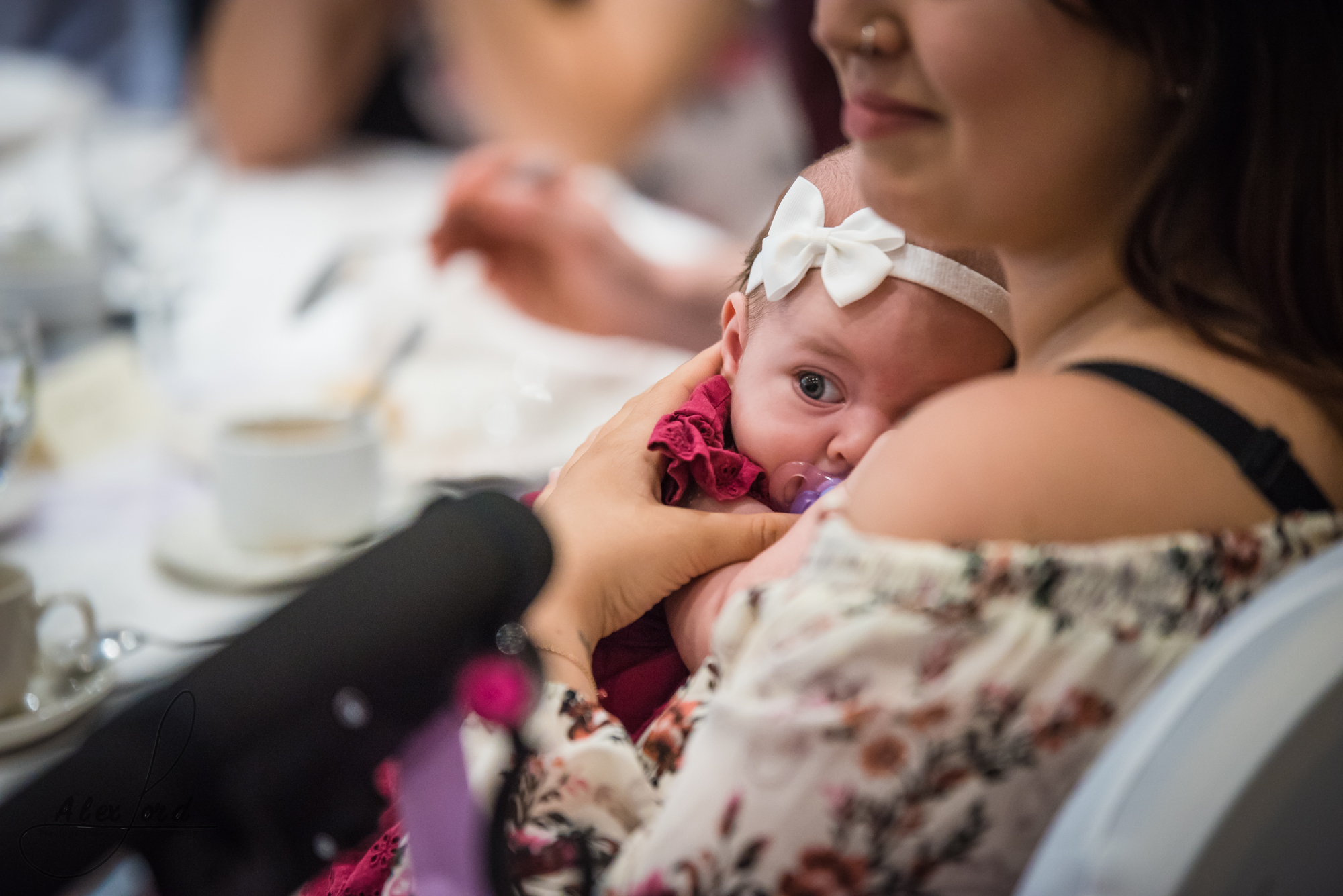 a young baby cuddles up to her mother during the wedding breakfast