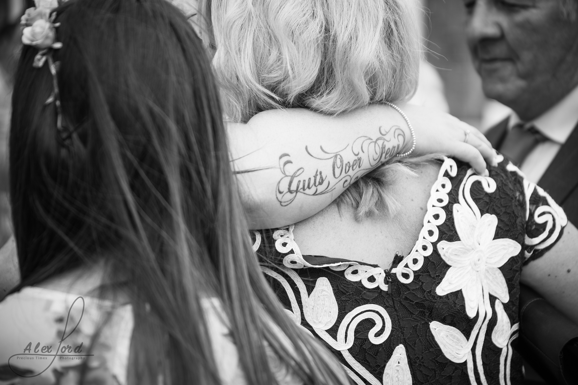 a tattoed arm wrapped around another guests shoulders