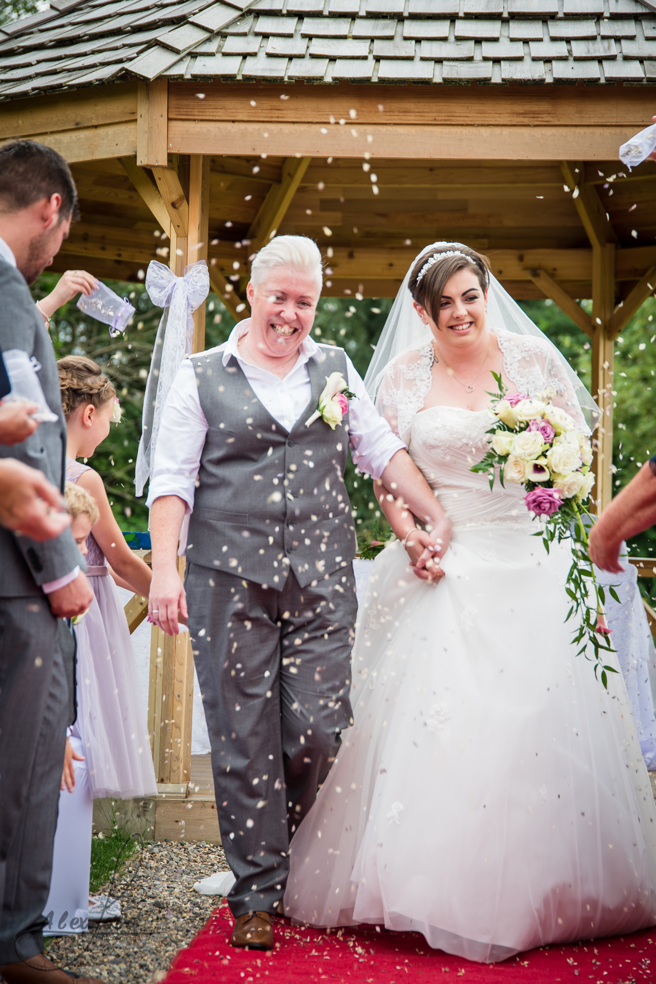 the Shropshire bride and bride walk down the aisle together getting covered in confetti