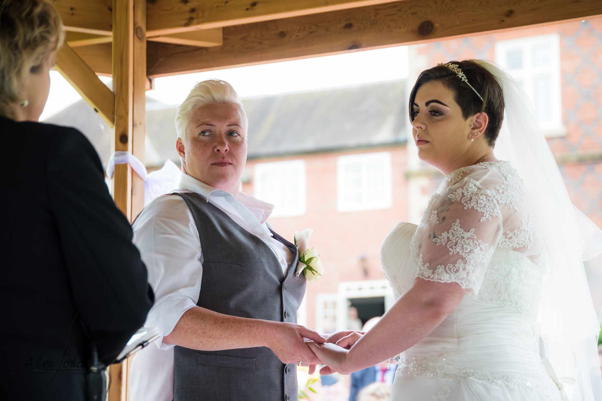 the bride and bride stand together saying their vows during their outdoor wedding ceremony