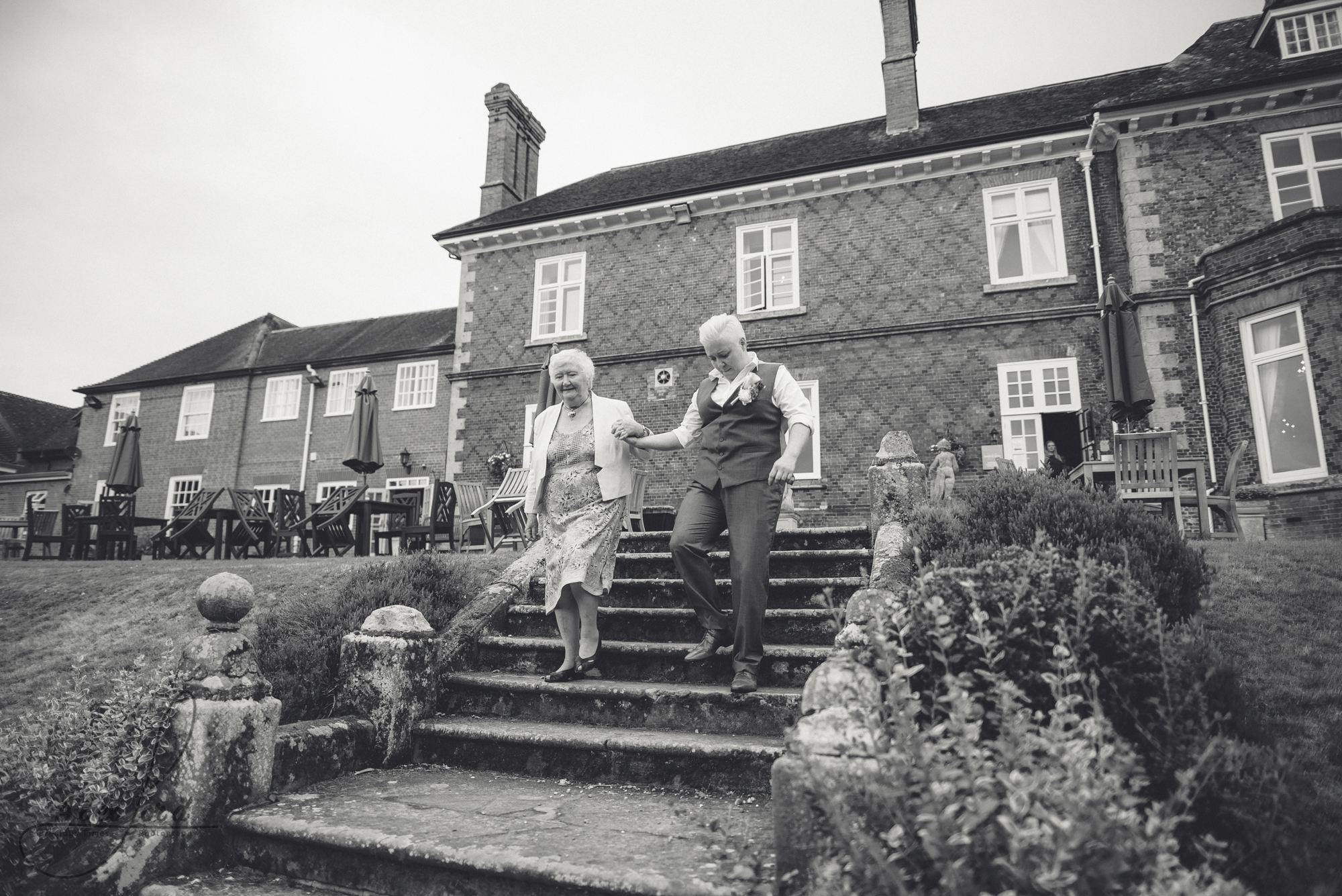 wedding guests walk down the steps of albrighton hall towards the gardens