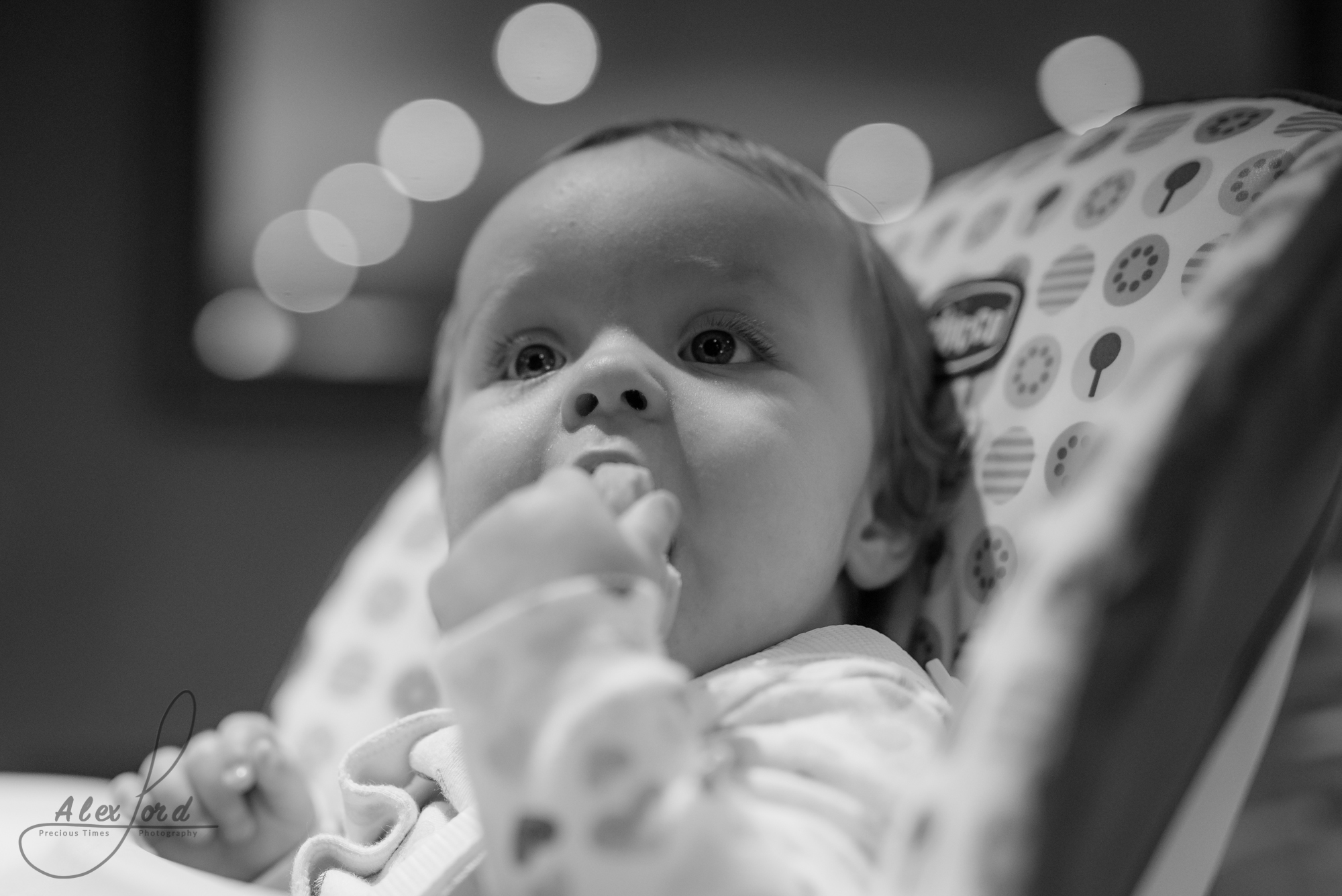 a young baby sits chewing on her fingers before the wedding ceremony