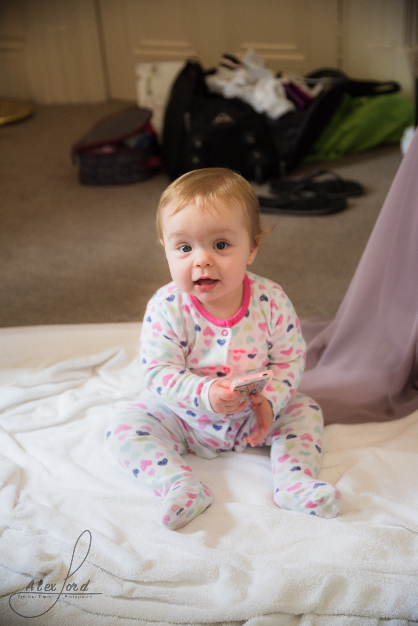 brides young baby sit on the wedding dress on the floor of the hotel room