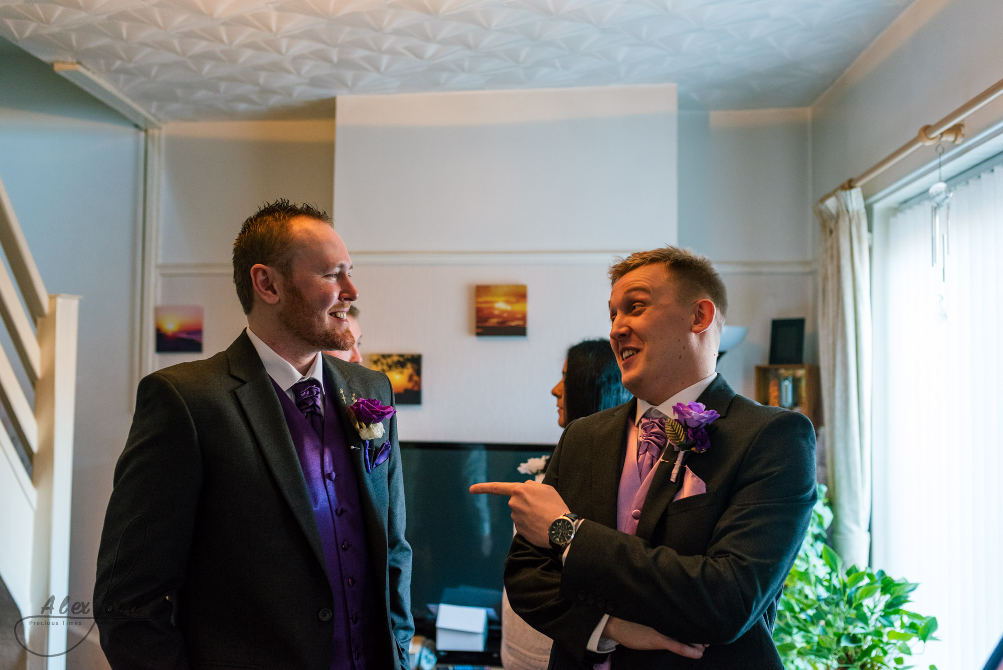 the groom and the best man have a laugh together in the middle of the living room before leaving for the wedding ceremony
