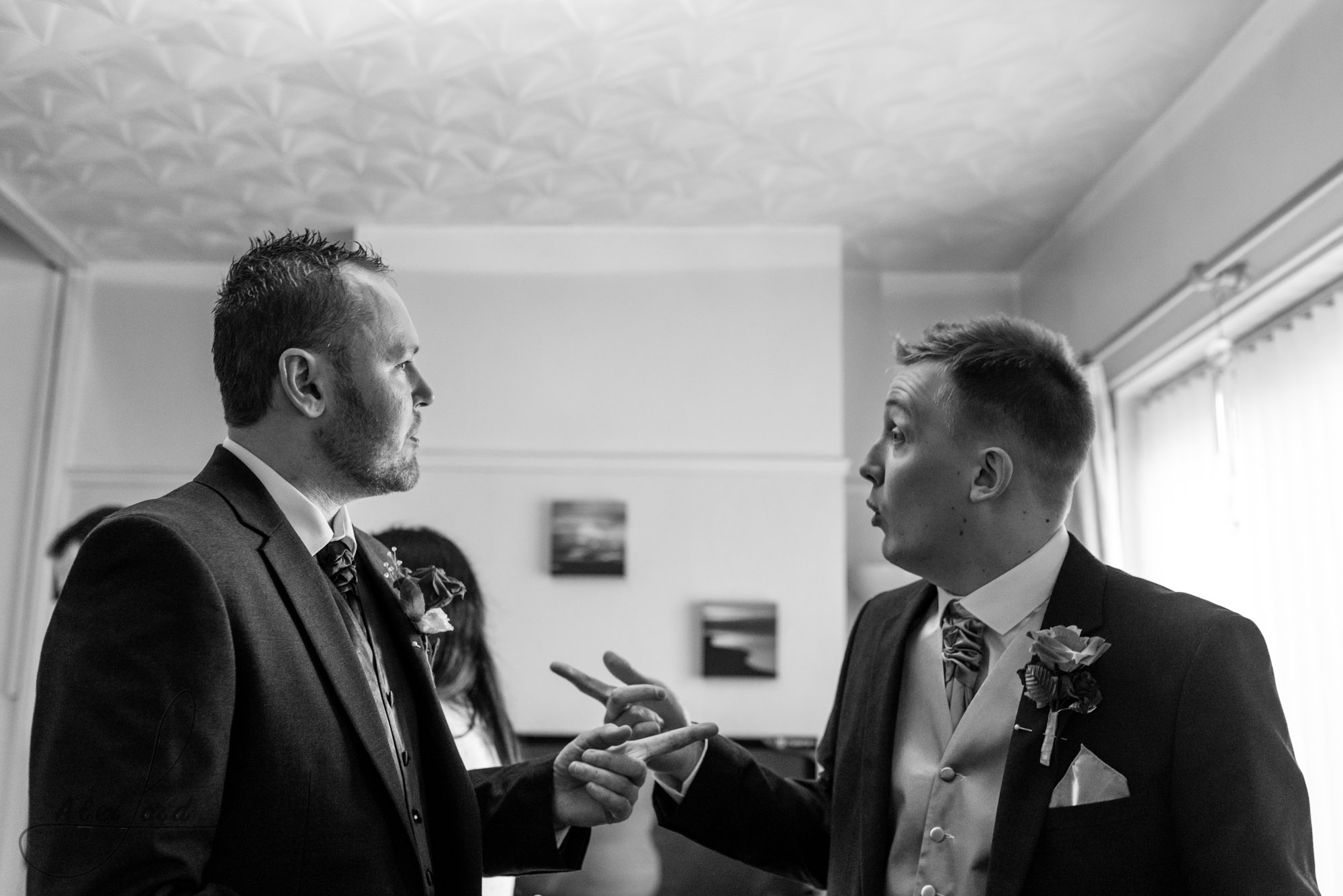 the bride and his best man stand chatting in the middle of the living room