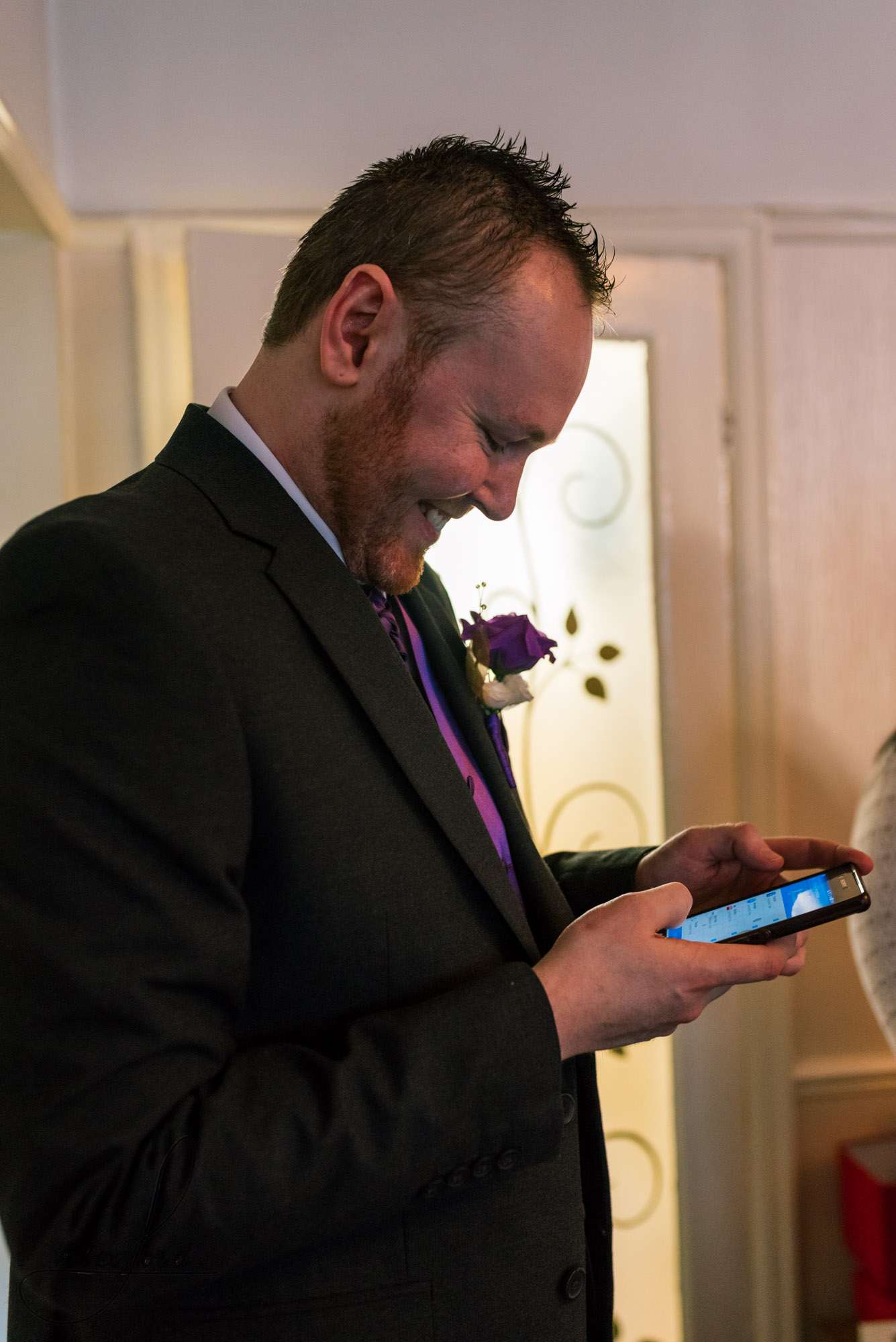 the groom checks his mobile phone before leaving for the ceremony