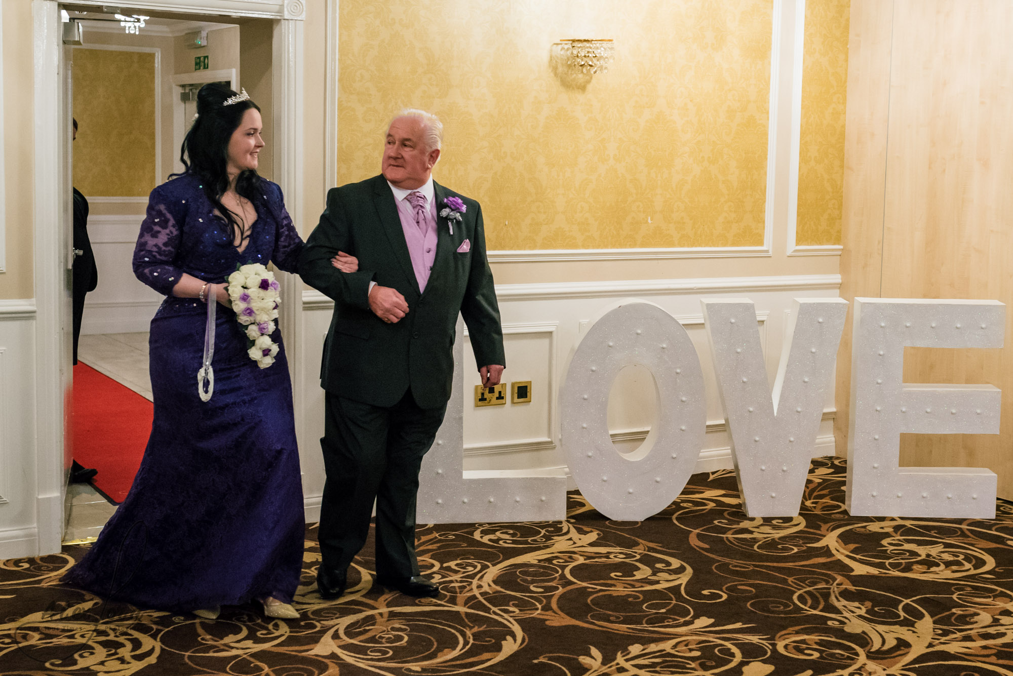 the bride and her father make an entrance into the wedding ceremony room