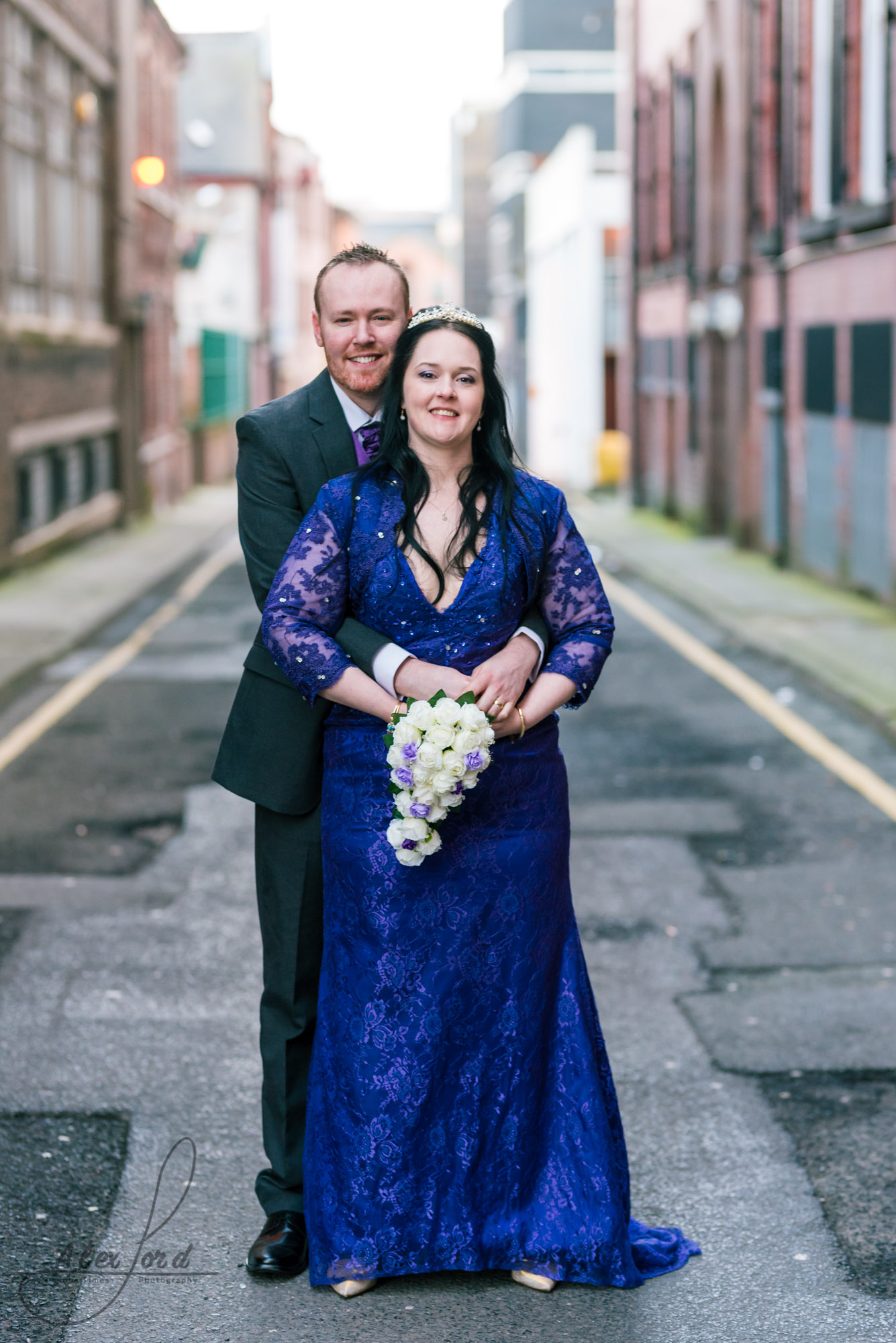 the bride and groom stand on a back street behind their liverpool wedding venue