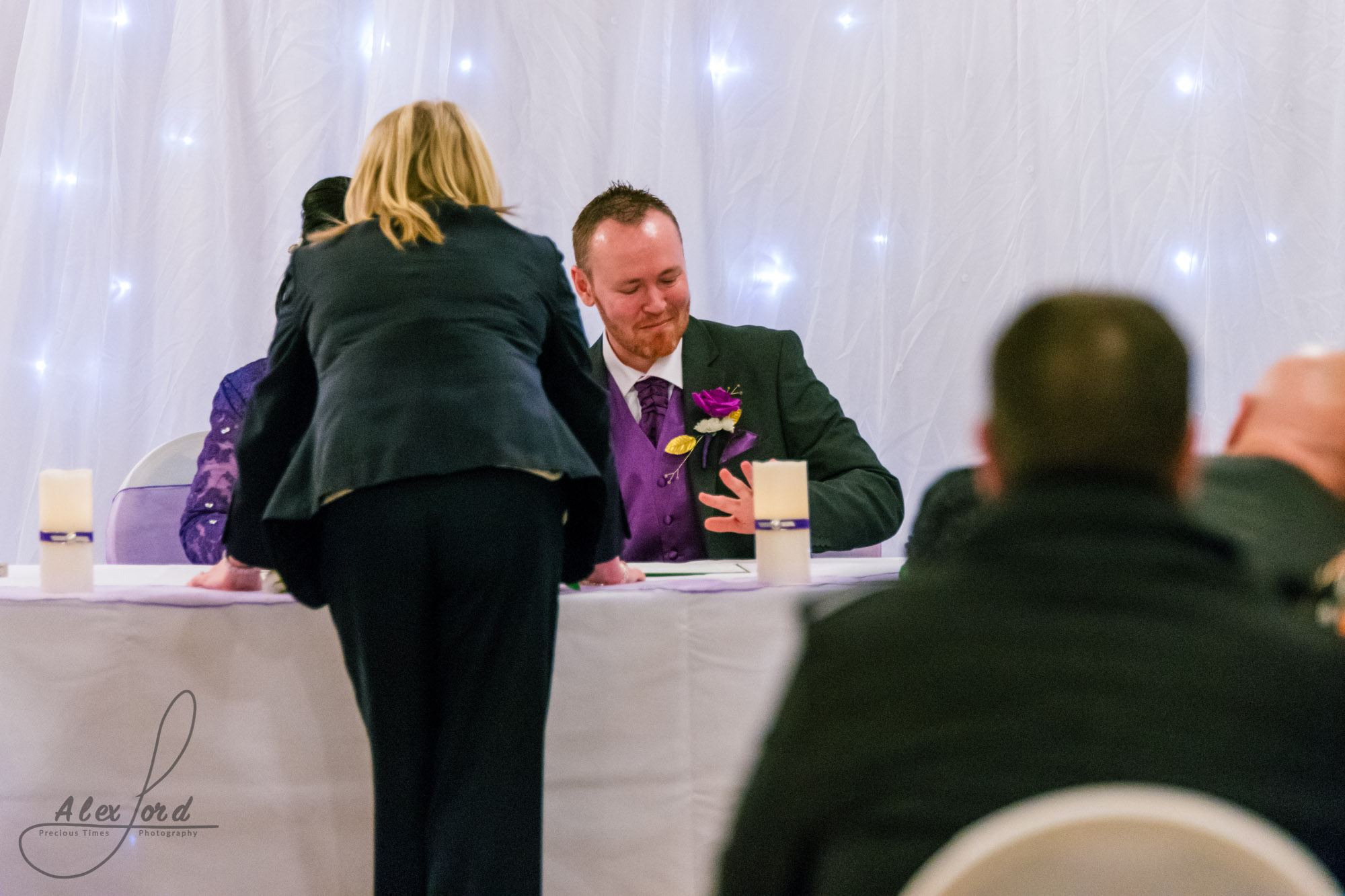 the groom is in view signing the marriage certificate while the registrar looks over them