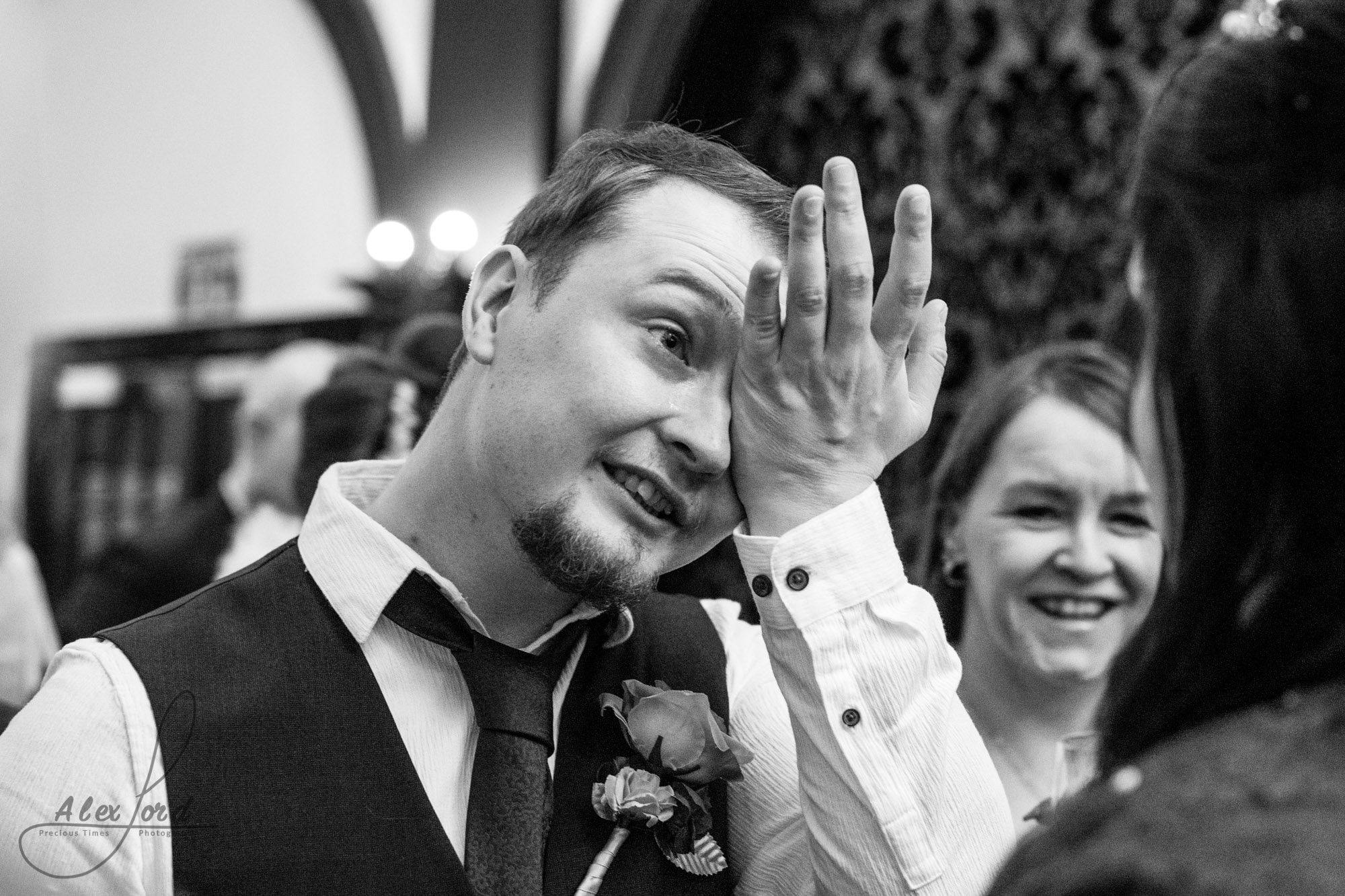 a male wedding guest puts his hand to his face to wipe away tears