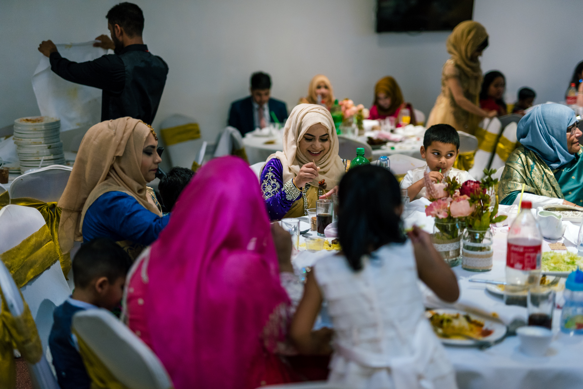 wedding guests sit round a table eating indian wedding food
