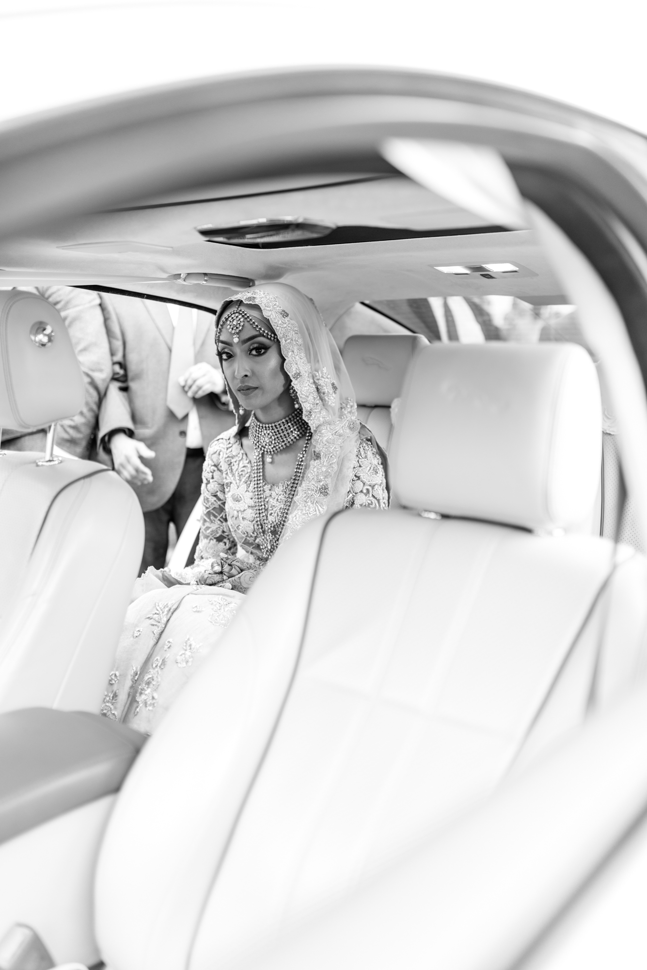 the bride sits in the car before the groom joins her to depart for their new life