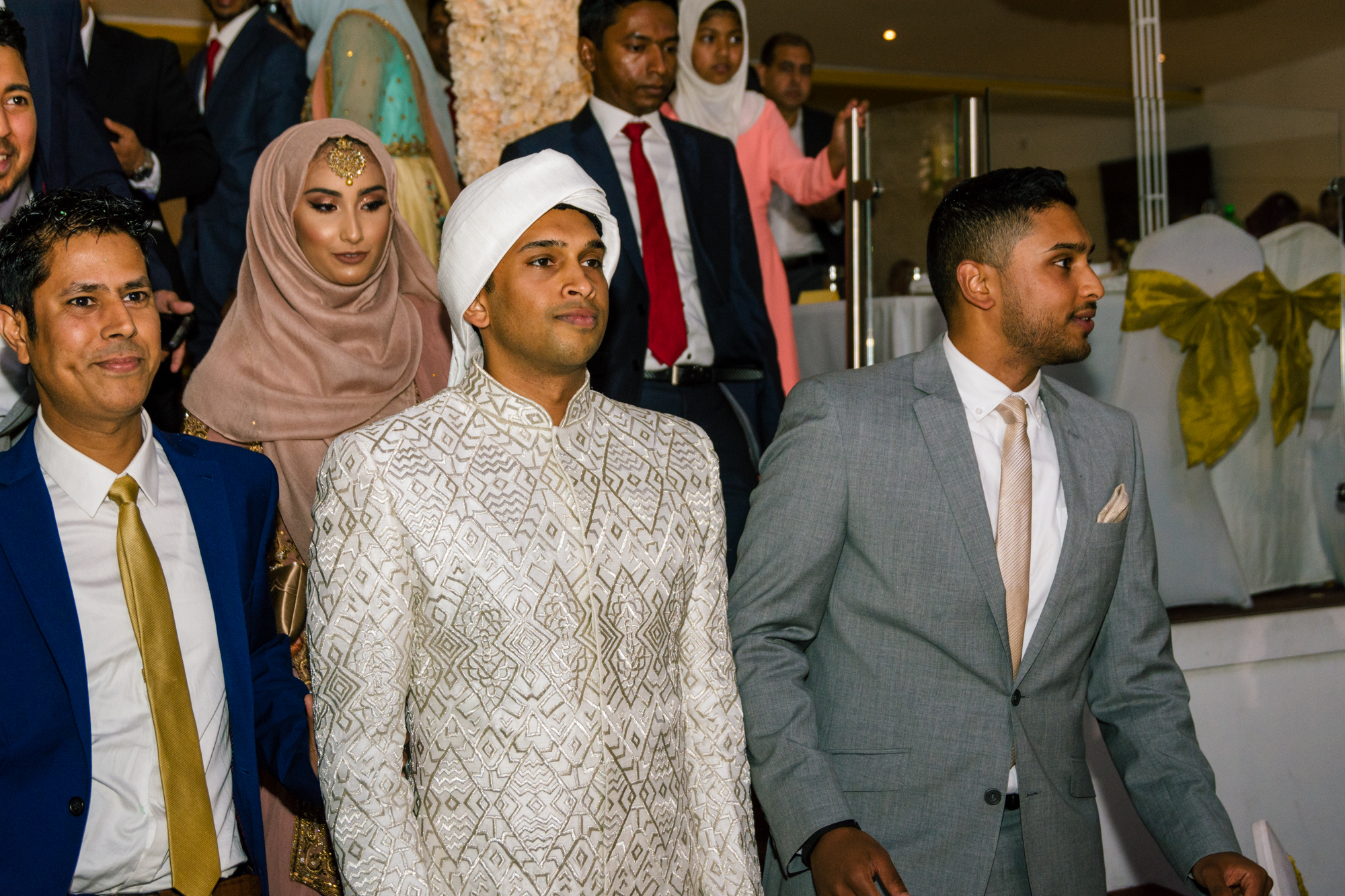 members of the grooms family escort the groom out of the wedding venue
