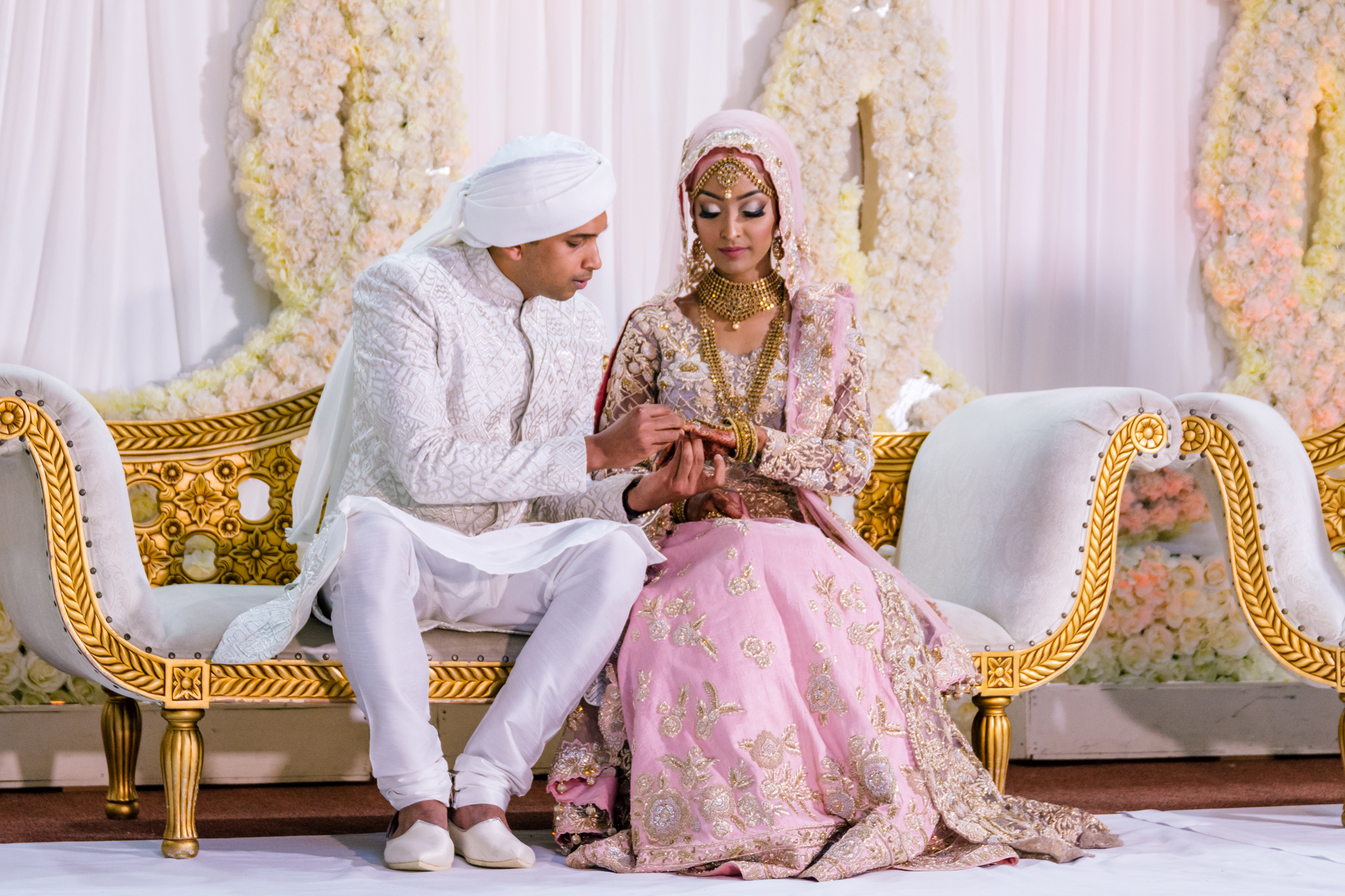 the bride and groom have a chat with each other whilst sitting on the stage in between official photos