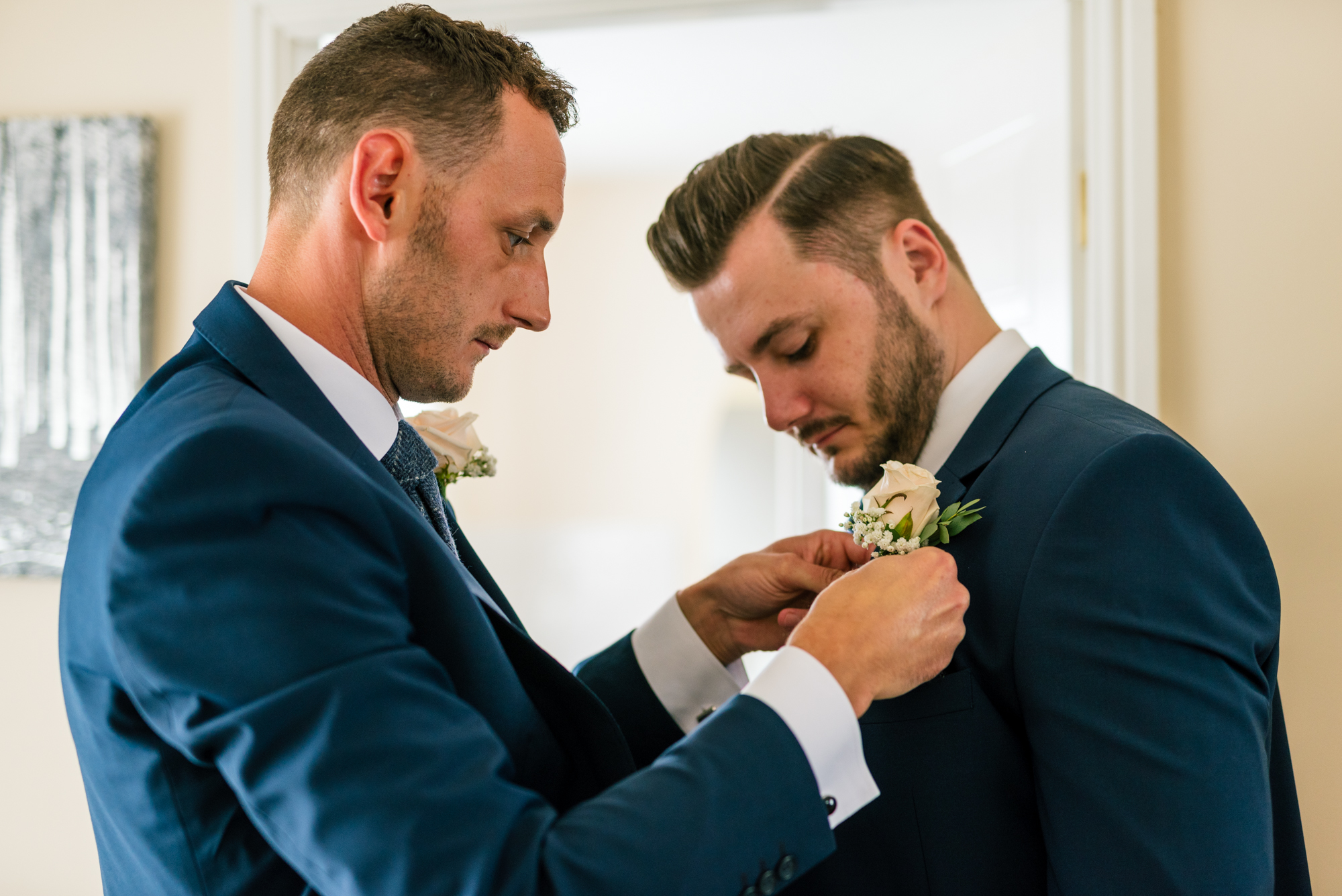best man putting the flower on the grooms jacket