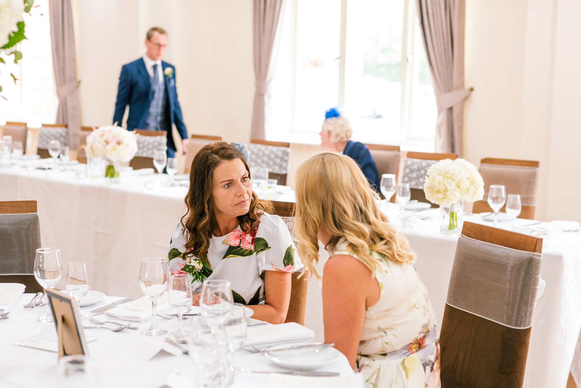 two wedding guests having a chat at a table
