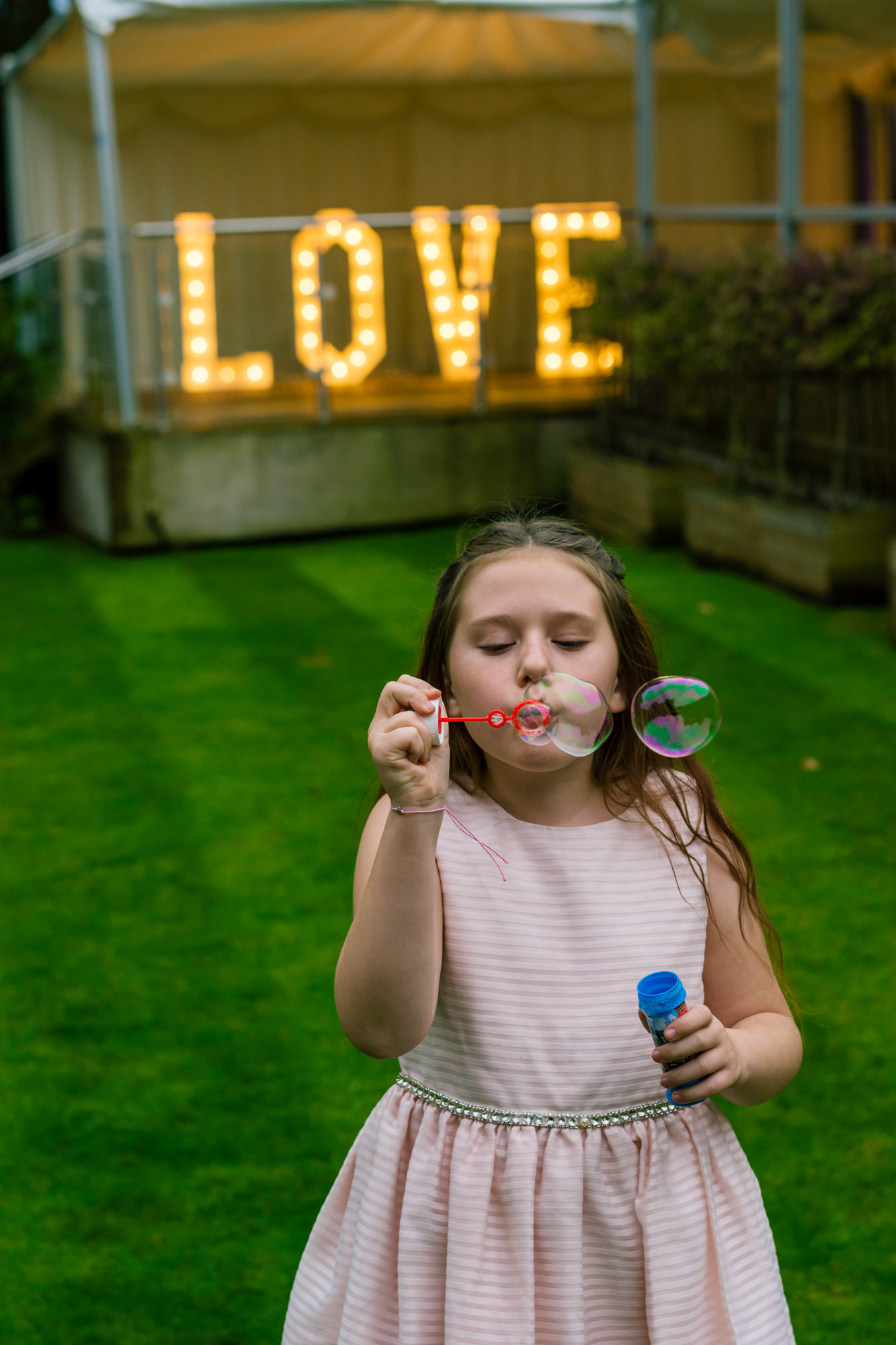 child blowing bubbles at a wedding