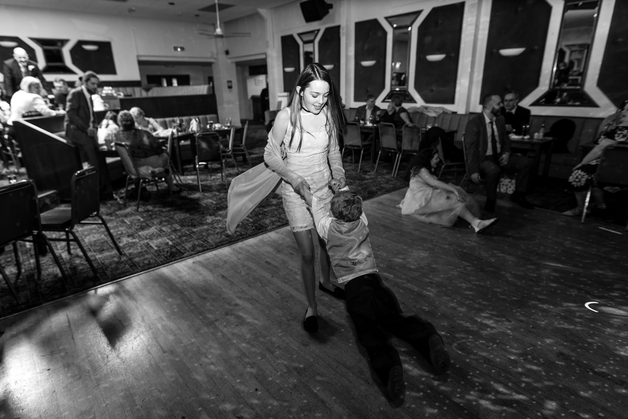 Two children, one spinning the other around on the dance floor.