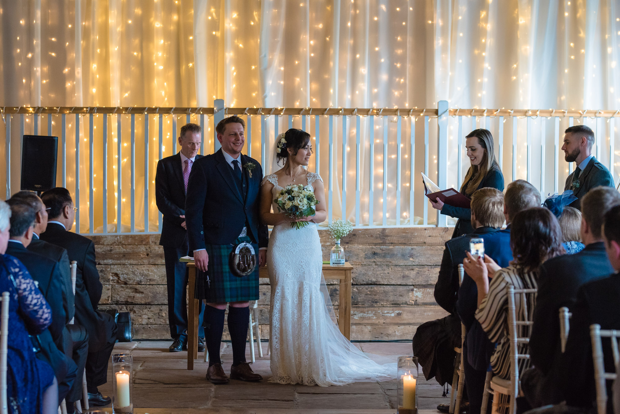 The bride and groom stand and face their guests at the end of their wedding ceremony at Askham Hall.