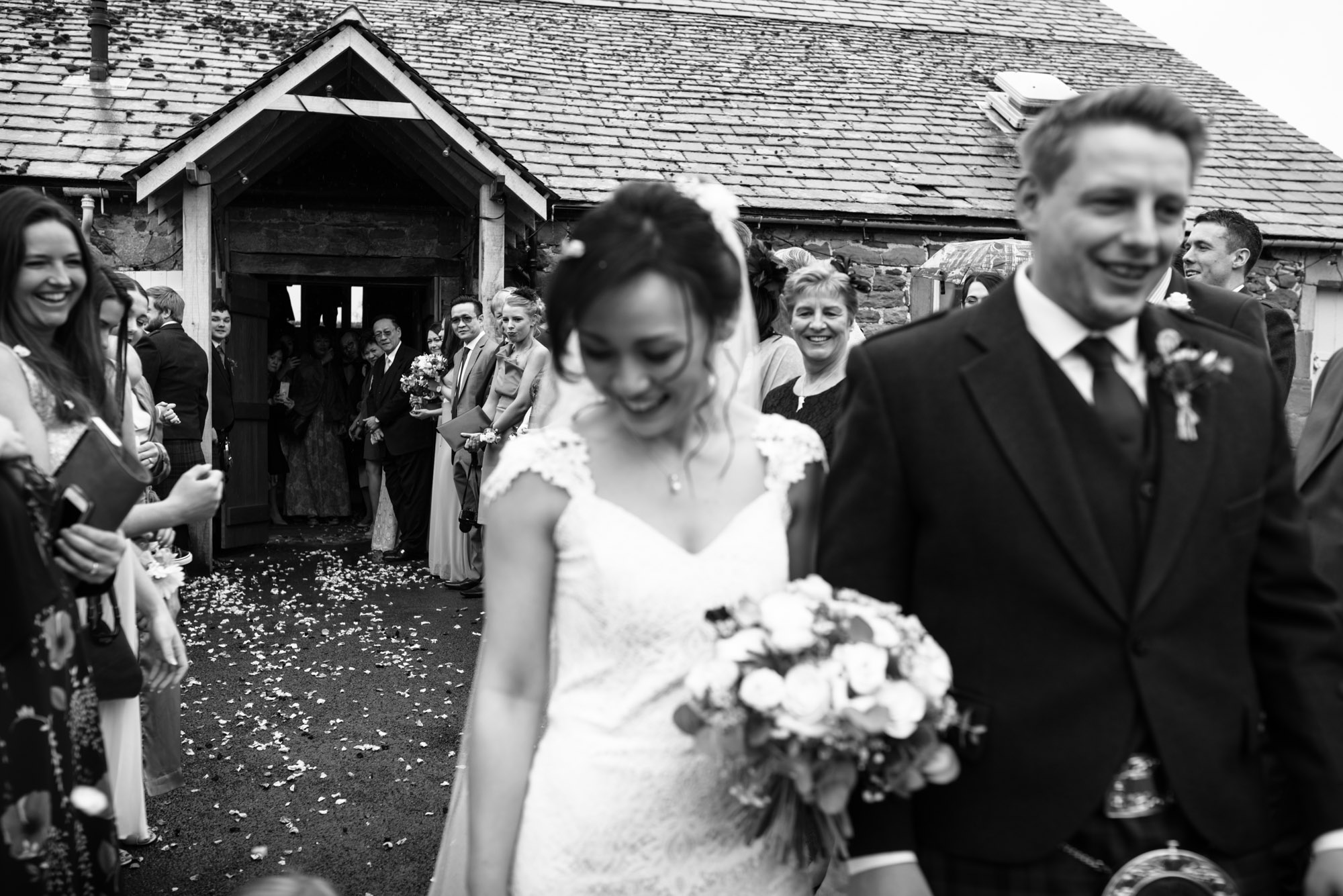 Guests are laughing and smiling at the very end of the confetti shot outside Askham Hall.